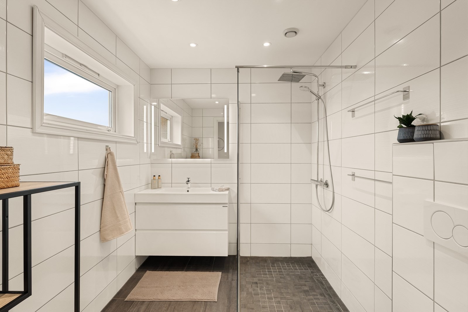 Badet er nydelig innredet med servant med møblement og speil, vegghengt toalett og dusjvegg. Galleribilde