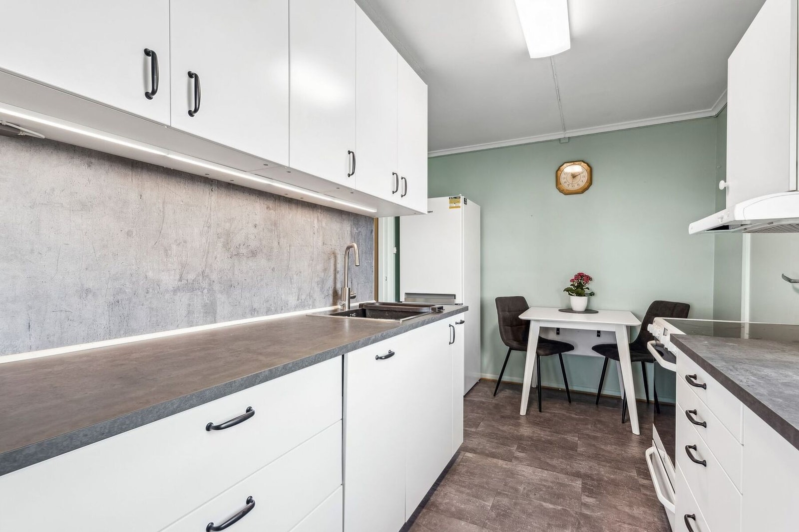 Kjøkkenet har frittstående hvitevarer som komfyr, innebygget oppvaskmaskin og kjøleskap. Galleribilde