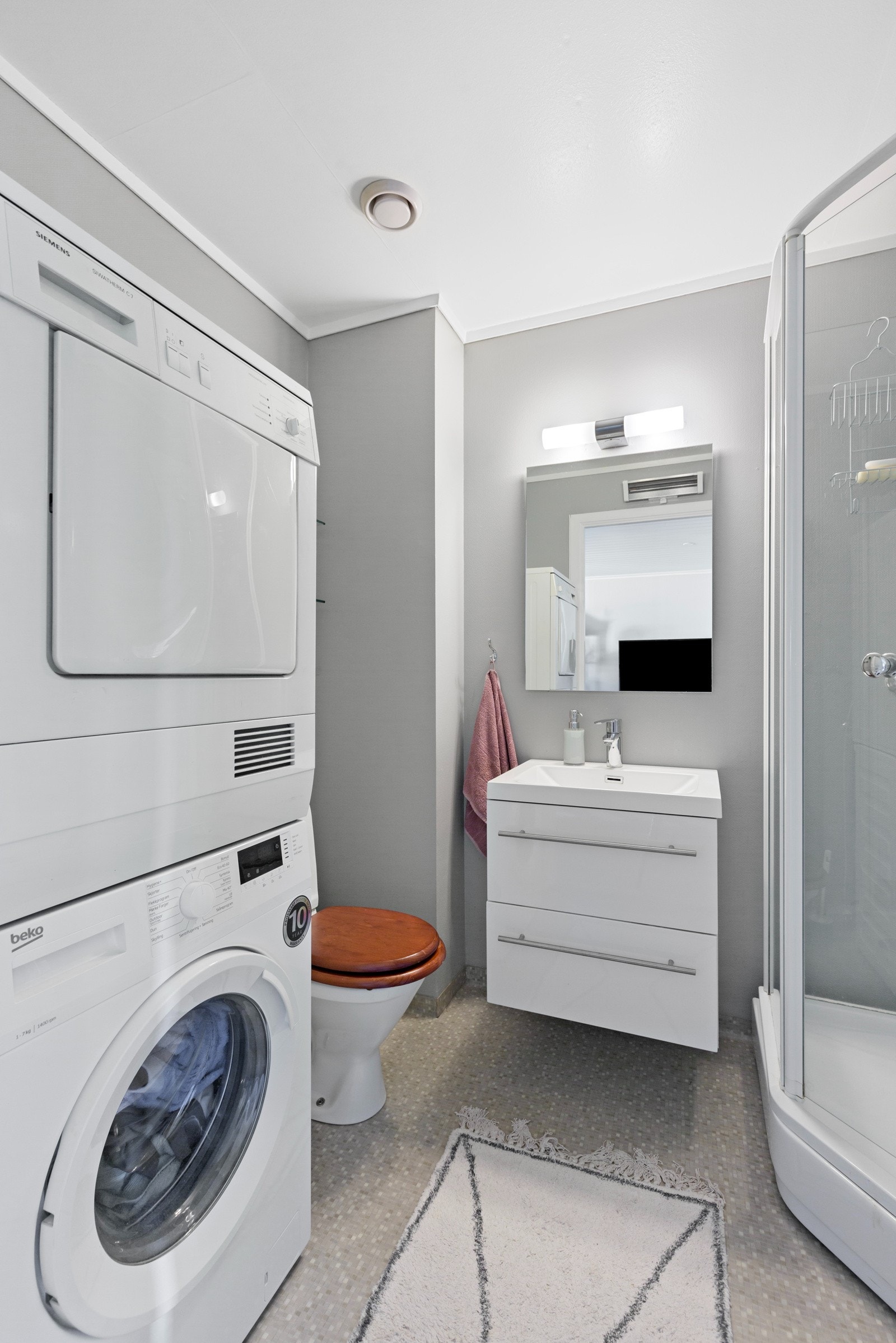 Badet har dusjkabinett, innredning med vask, wc og opplegg til vaskemaskin Galleribilde