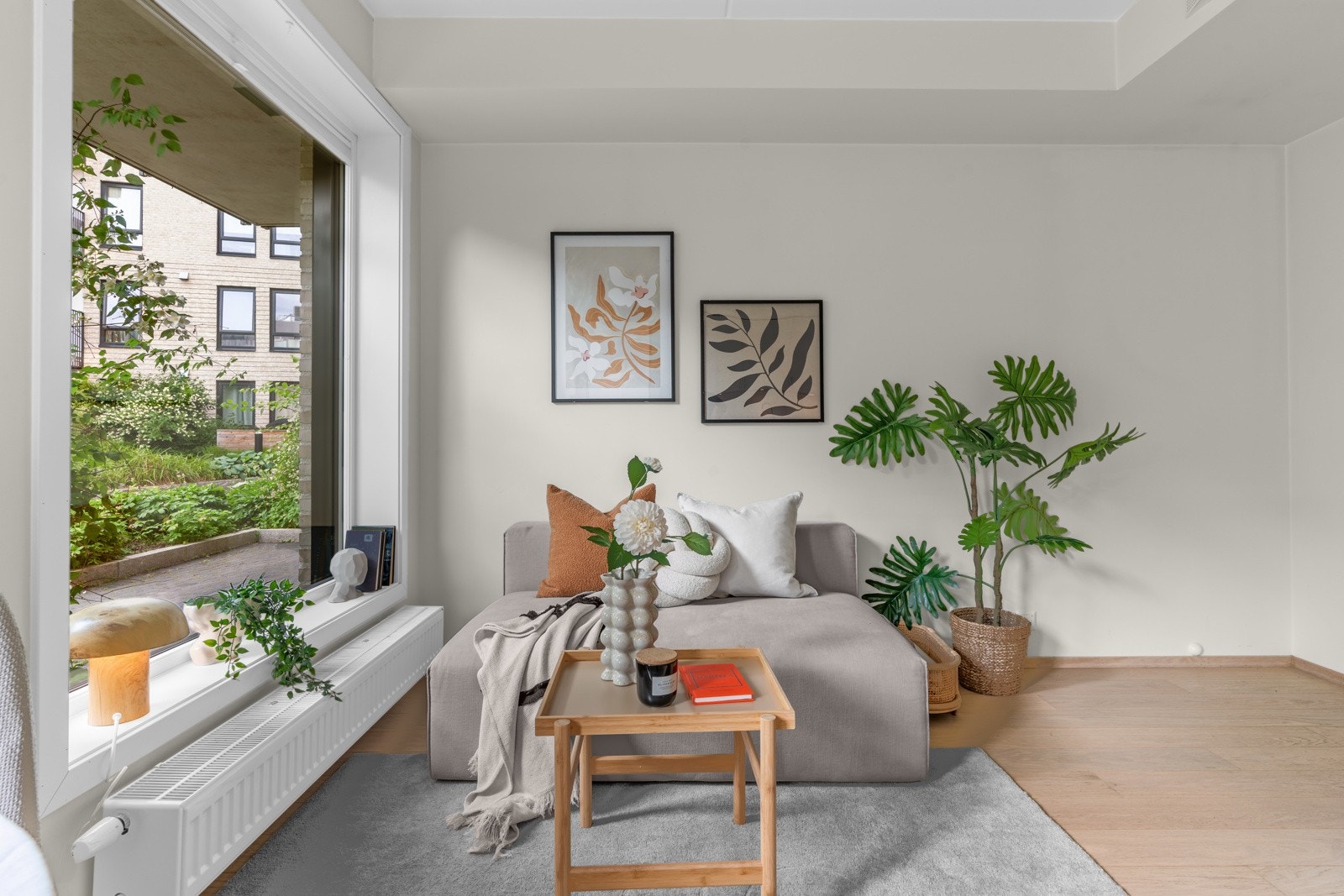Lysmalt stue med store vindusflater og en vinduskarm som planter kan trives i. Galleribilde