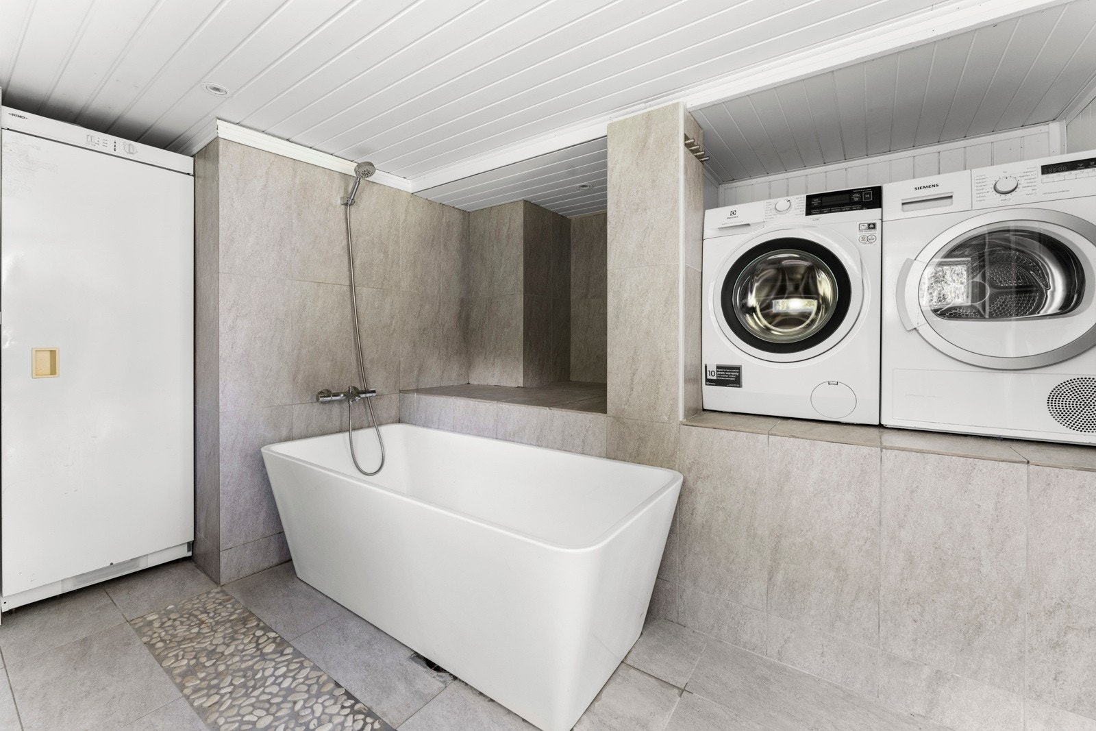 Badet i underetasjen har badekar og nisje til vaskemaskin og tørketrommel. Varmtvannsbereder på 200 l er i kjeller. Galleribilde