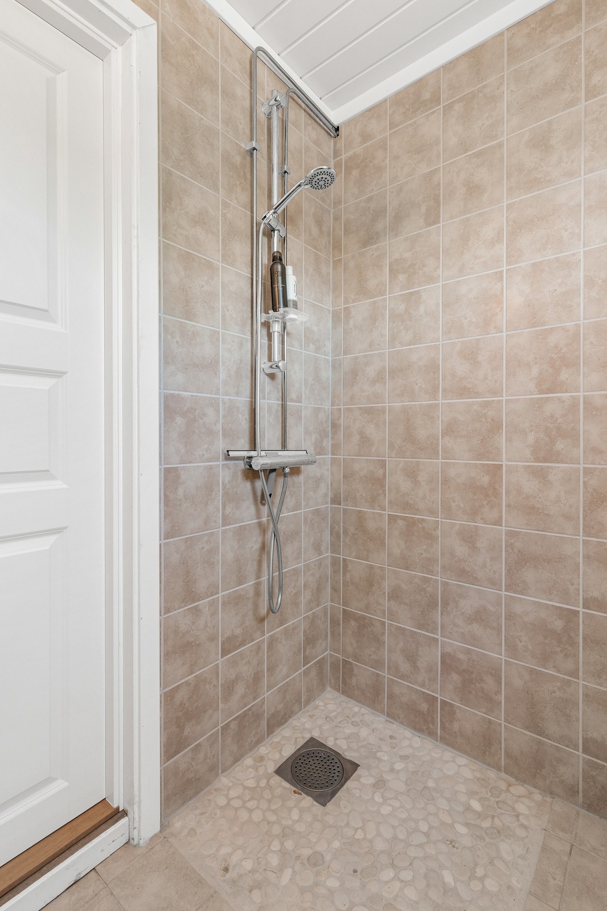 Badet er innredet med gulvstående toalett, servantinnredning og dusjhjørne med vegghengt dusjarmatur Galleribilde