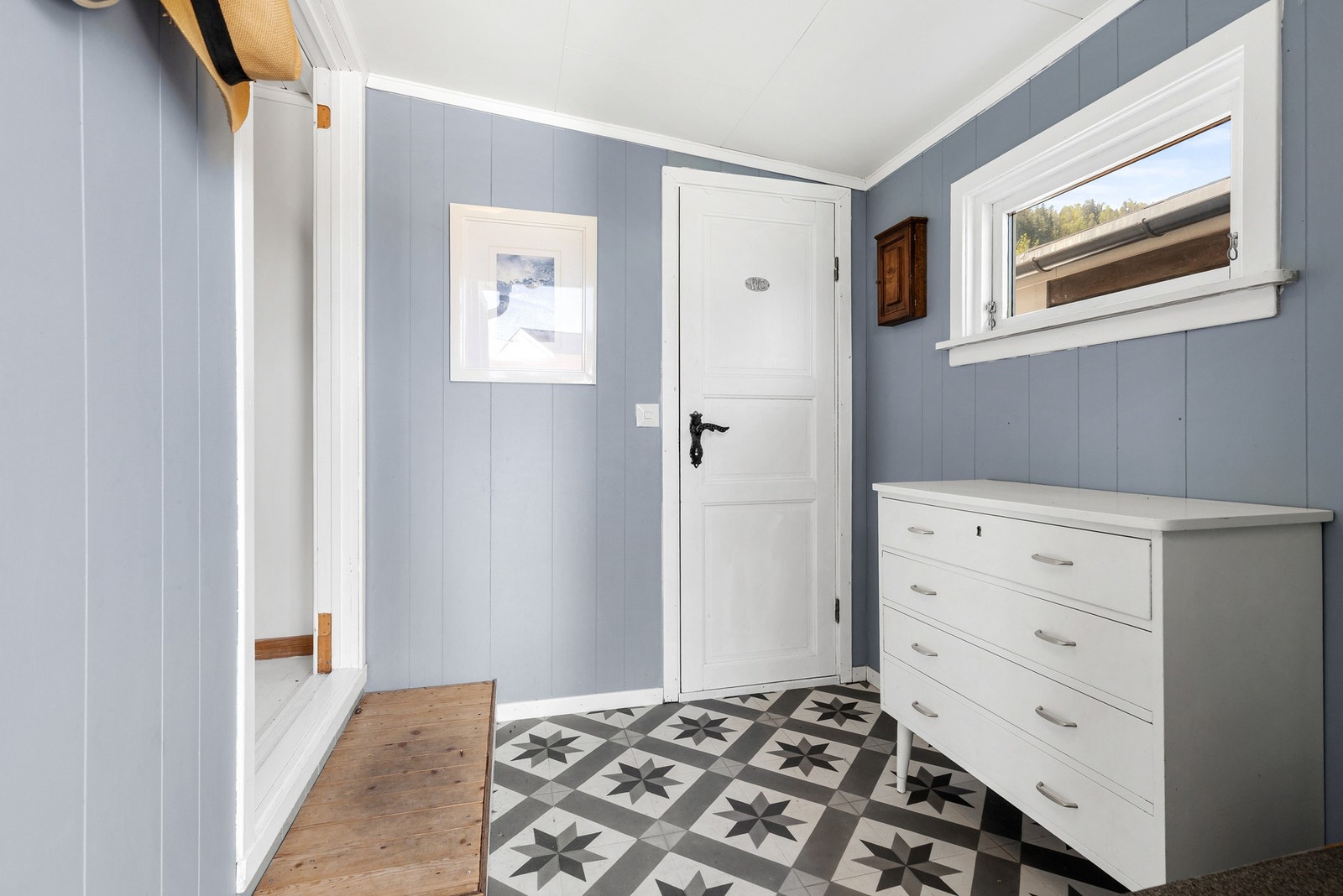 Romslig entré med belegg på gulv, malt panelvegger og takplater i himling Galleribilde