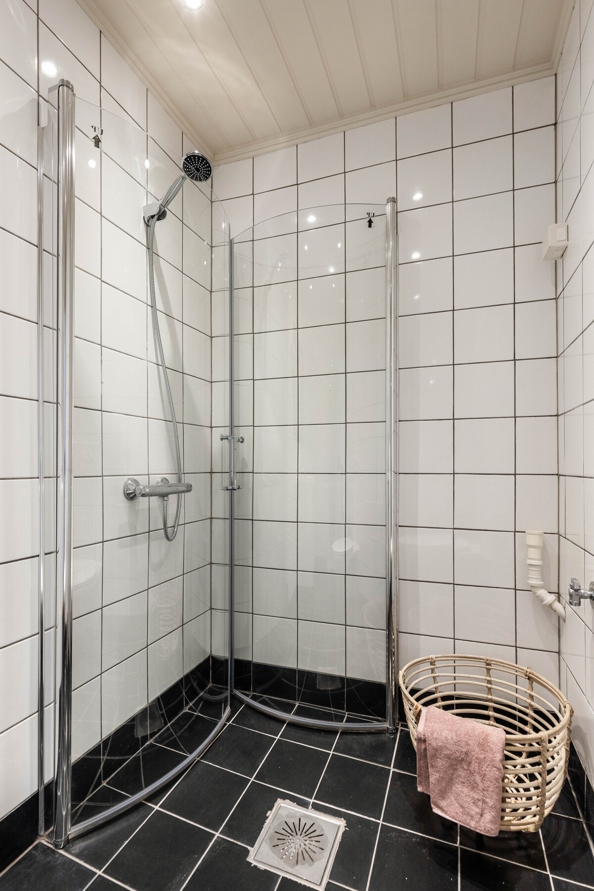 Dusjhjørne med glassdører, hvite fliser på vegger og svart flislagt gulv. Galleribilde