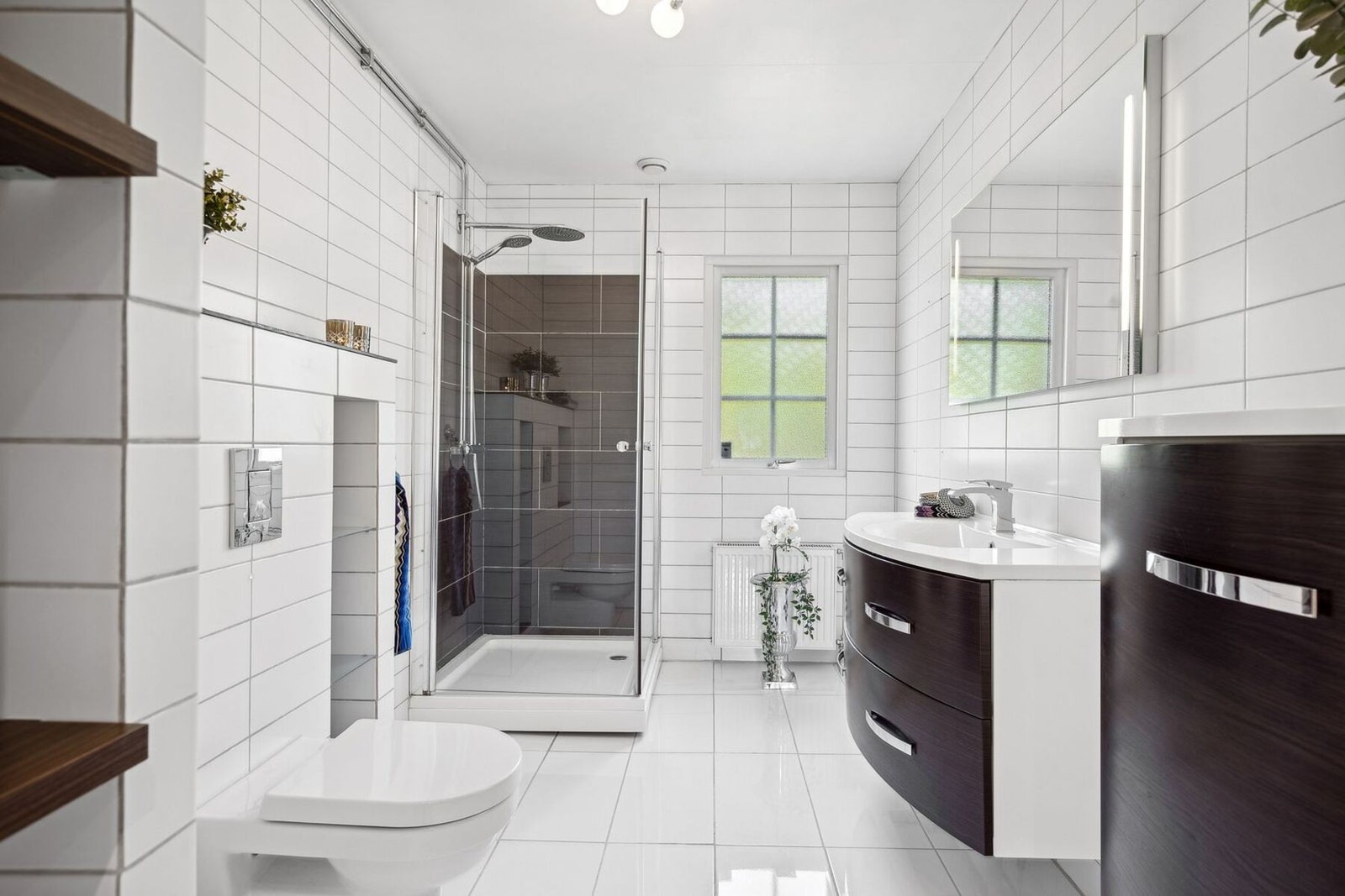 Delikat baderom i 1. etasje med innredning, veggmontert toalett og dusjkabinett. Galleribilde