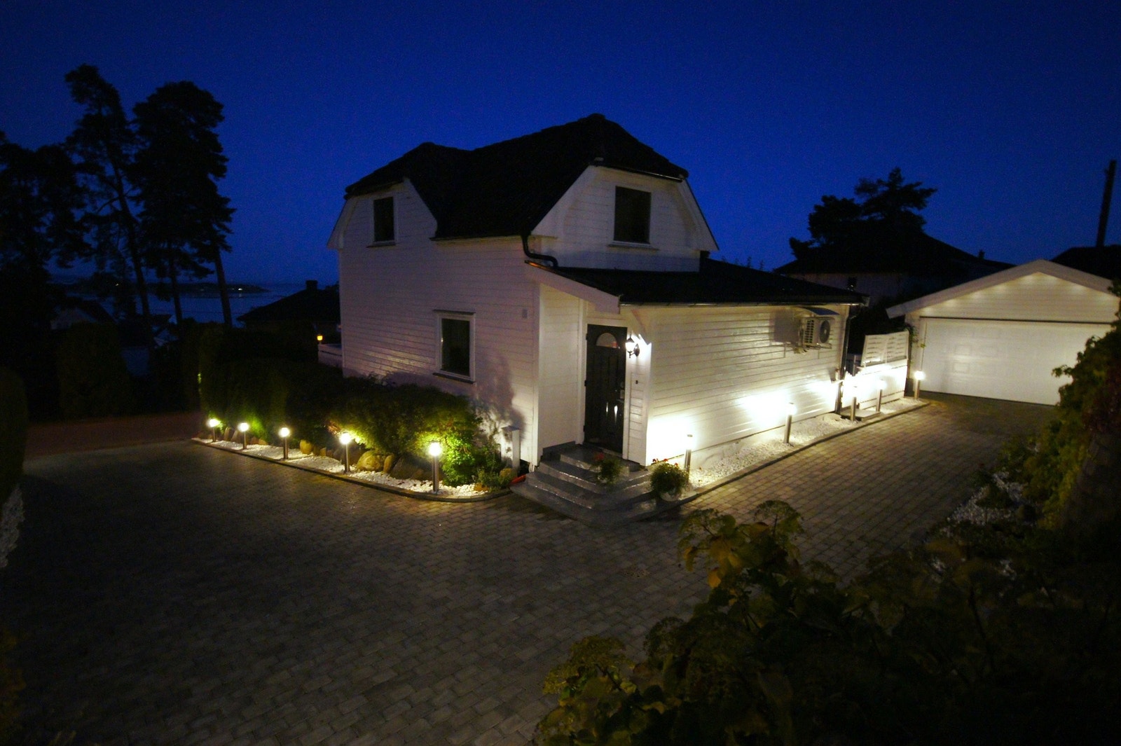Huset om kvelden med belysning av innkjørselen. Galleribilde
