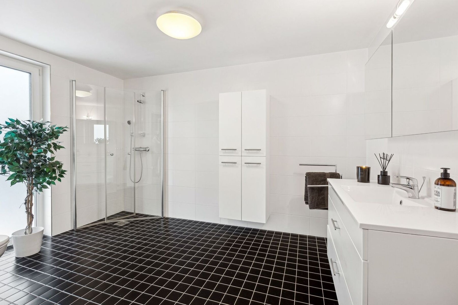 Begge badene er i moderne stil med mørke gulvfliser og hvite fliser på veggene, dette gir et stilrent og tidløst preg. Galleribilde