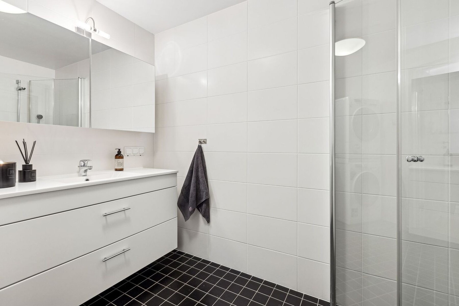 Begge baderommene er utstyrt med fliser på gulv og vegger, hvit servantinnredning med skuffeseksjon og dusjhjørne med glassdører. Galleribilde