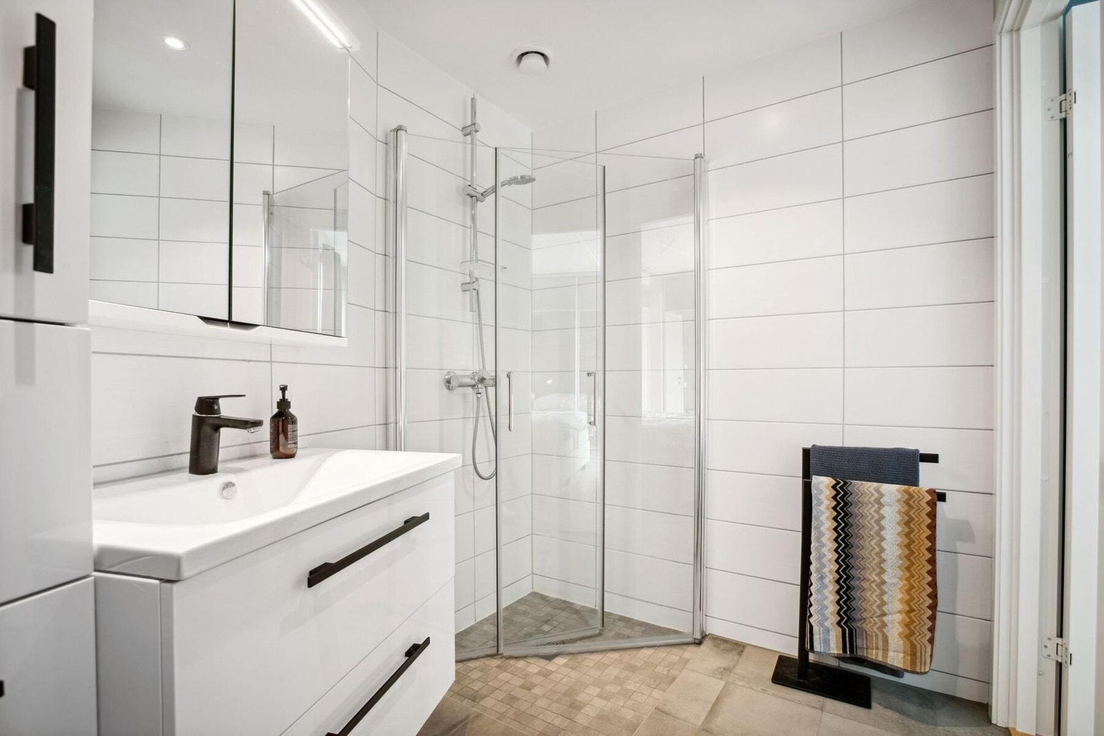 Baderommet har lys innredning med servant, toalett og dusjhjørne med innfellbare glassvegger. Galleribilde