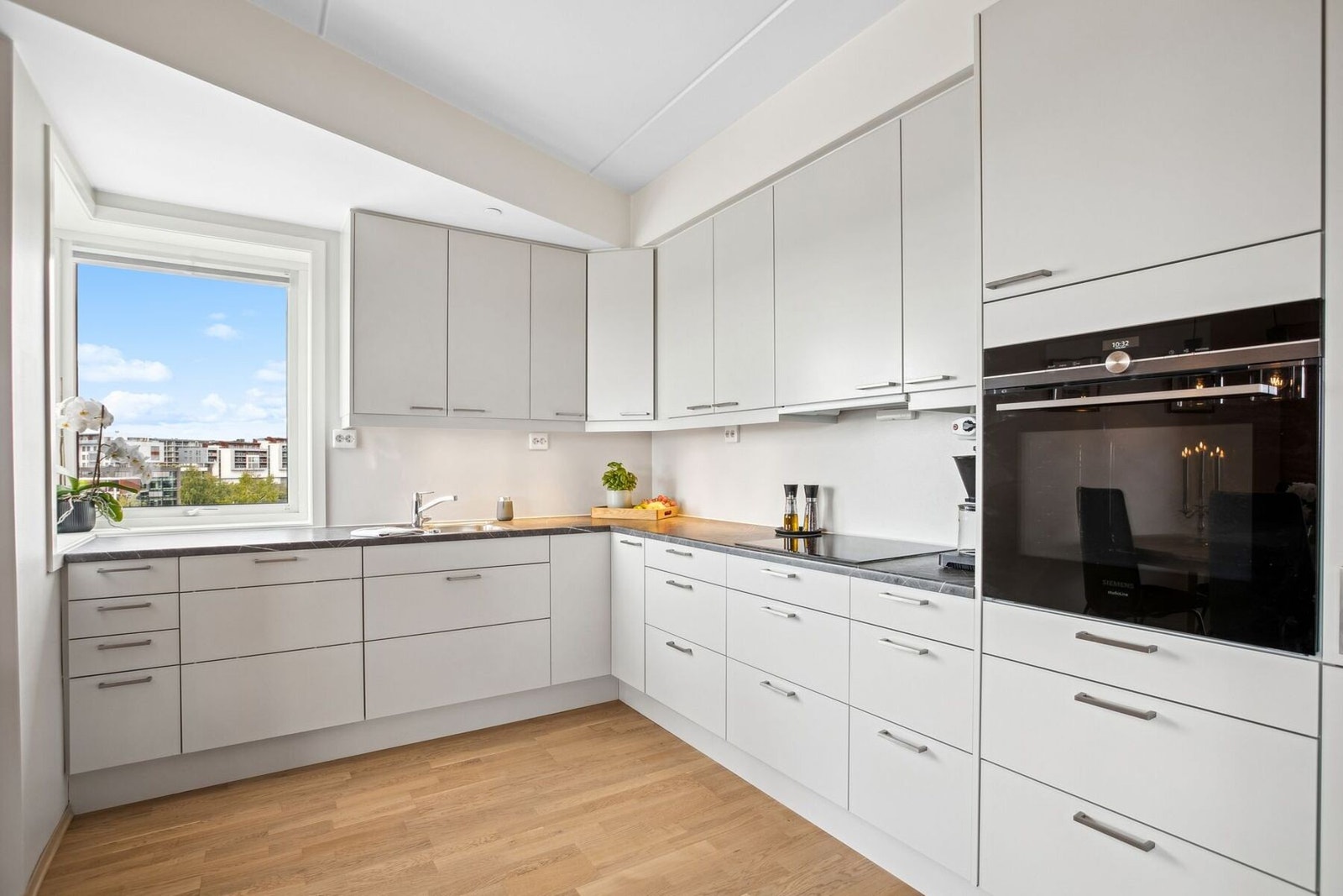 Kjøkkeninnredning med glatte fronter, benkeplater i laminat, oppvaskkum med ett-greps blandebatteri og ventilator over kokesonen. Galleribilde