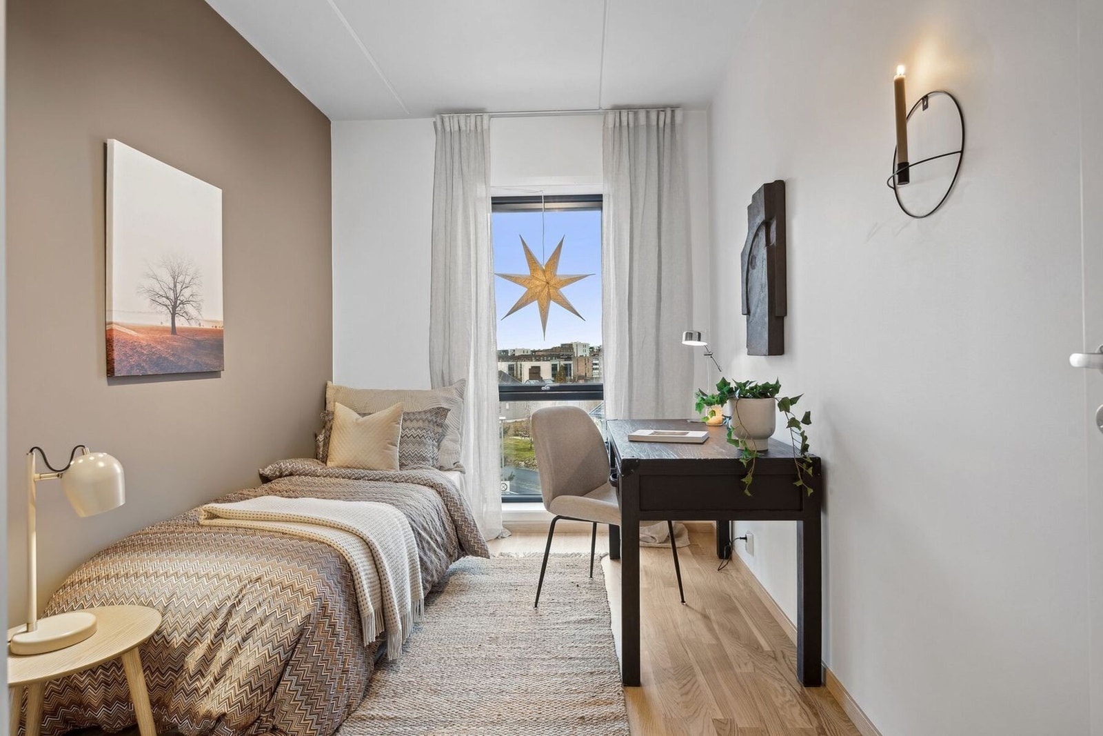 Koselig og funksjonelt soverom som kombinerer ro og kreativitet. De varme jordtonene på veggene skaper en behagelig atmosfære, mens det store vinduet slipper inn naturlig lys og gir en åpen følelse. Galleribilde