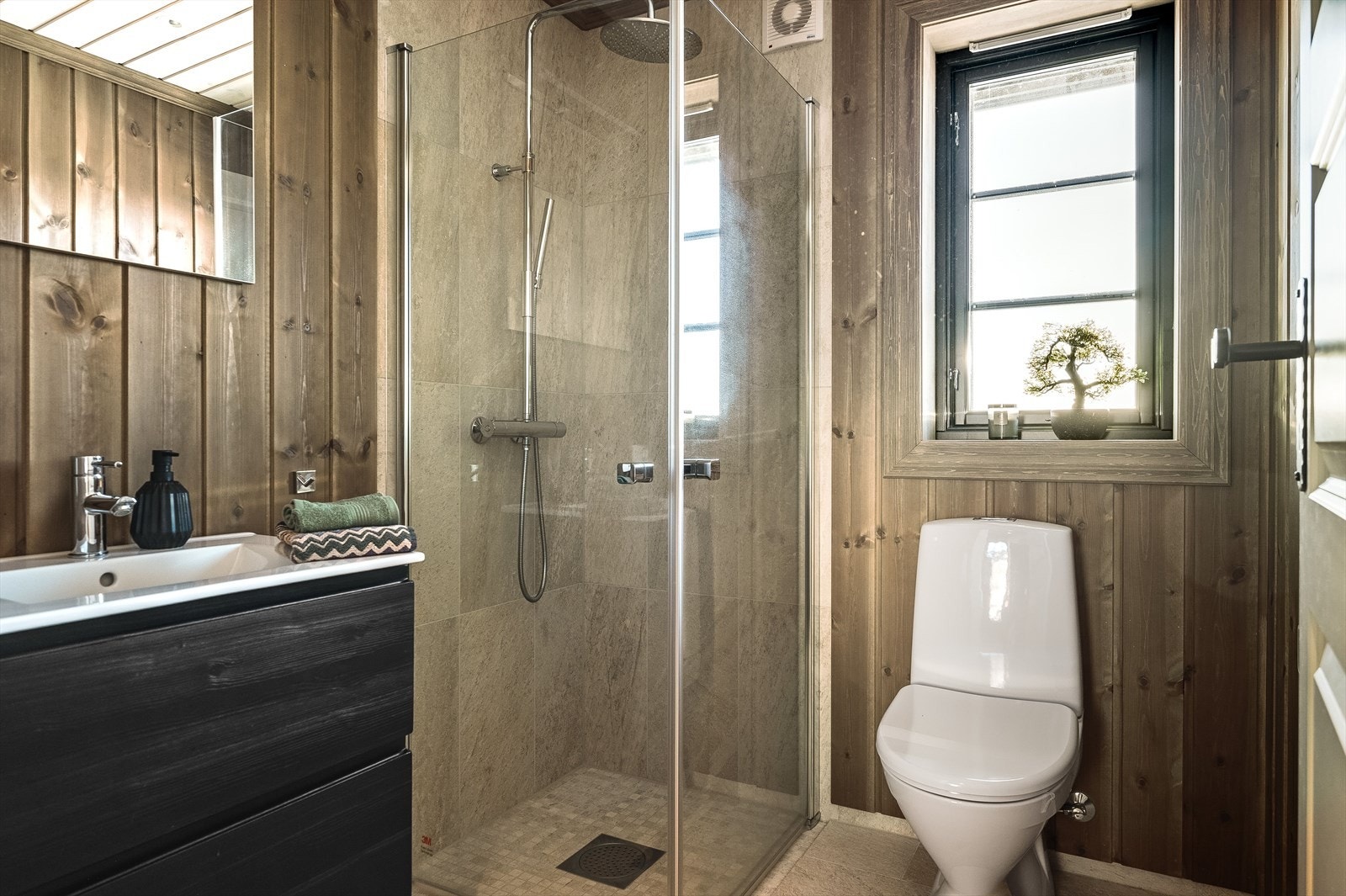 Innbydende baderom 2 fra 2021 med lekre farge- og materialvalg! Baderommet har flislagt gulv med gulvvarme, overflater med panel kombinert med fliser i dusjsonen, downlights i himlingen og mekanisk avtrekk. Galleribilde