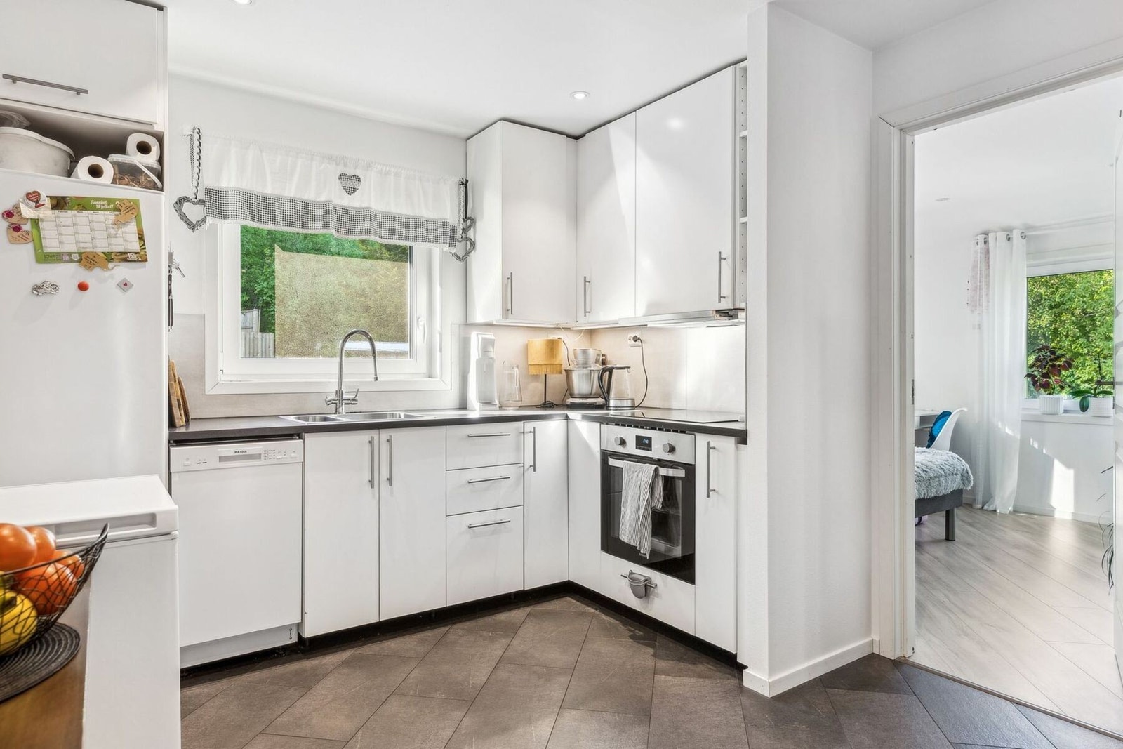 Kjøkken fra 2019 med lys innredning og delvis integrerte hvitevarer. Galleribilde