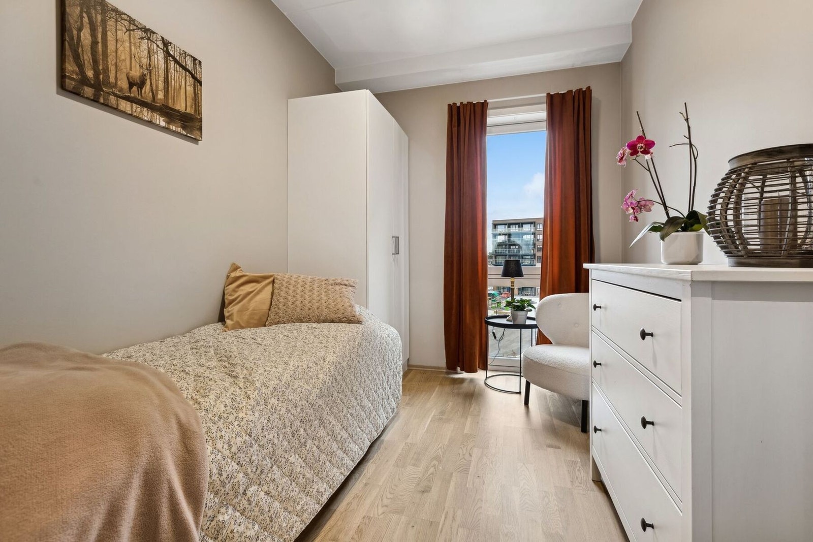 Dette rommet er perfekt som gjesterom, barnerom eller et fredelig kontor. Med de varme tonene i veggene og gardinene, samt naturlig lys fra vinduet, skapes en lun og koselig atmosfære. Galleribilde