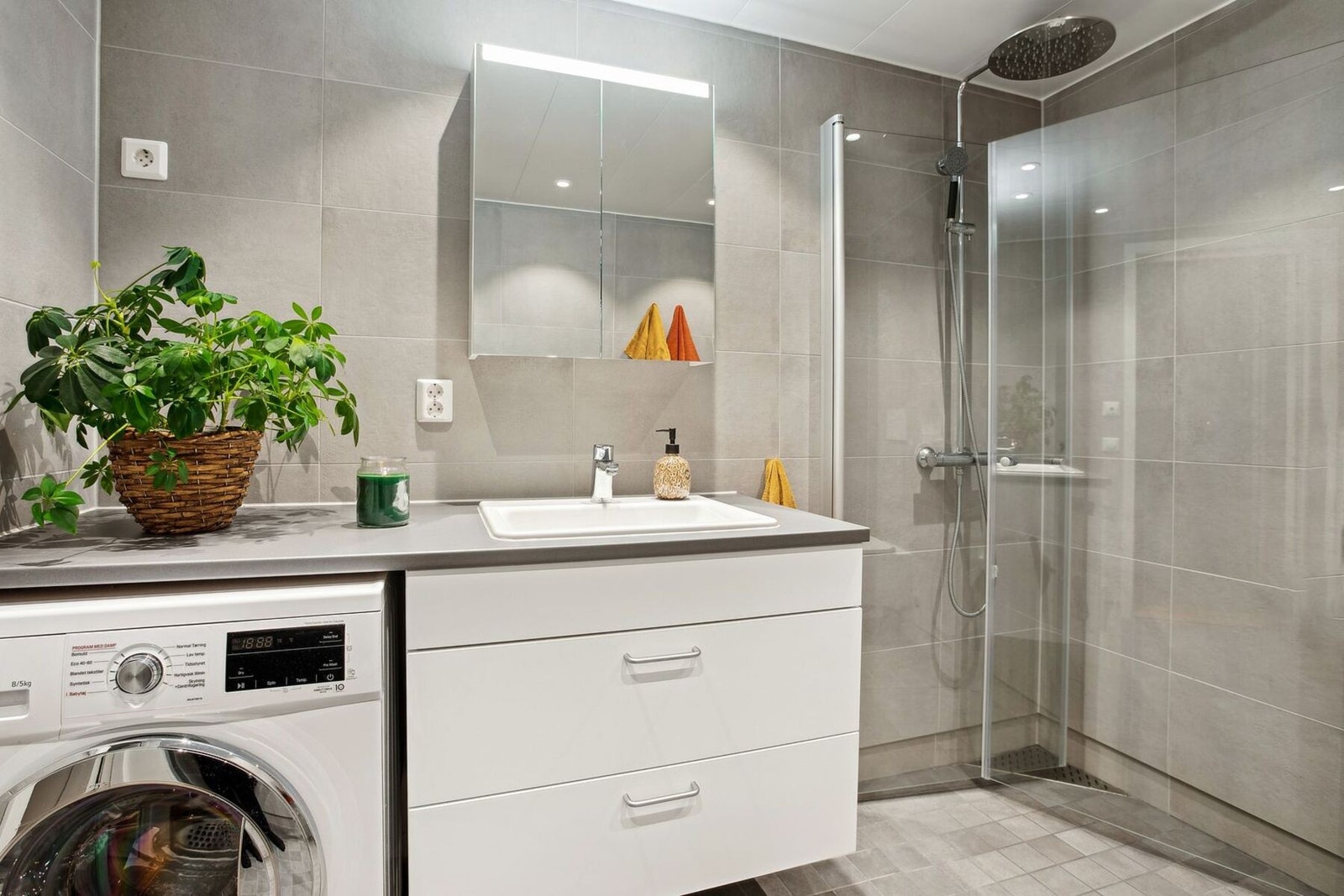 Videre kommer vi inn til dette elegante badet som kombinerer funksjonalitet med moderne estetikk. Med sine store grå fliser og integrerte dusjnisje er rommet både praktisk og stilfullt.v Galleribilde