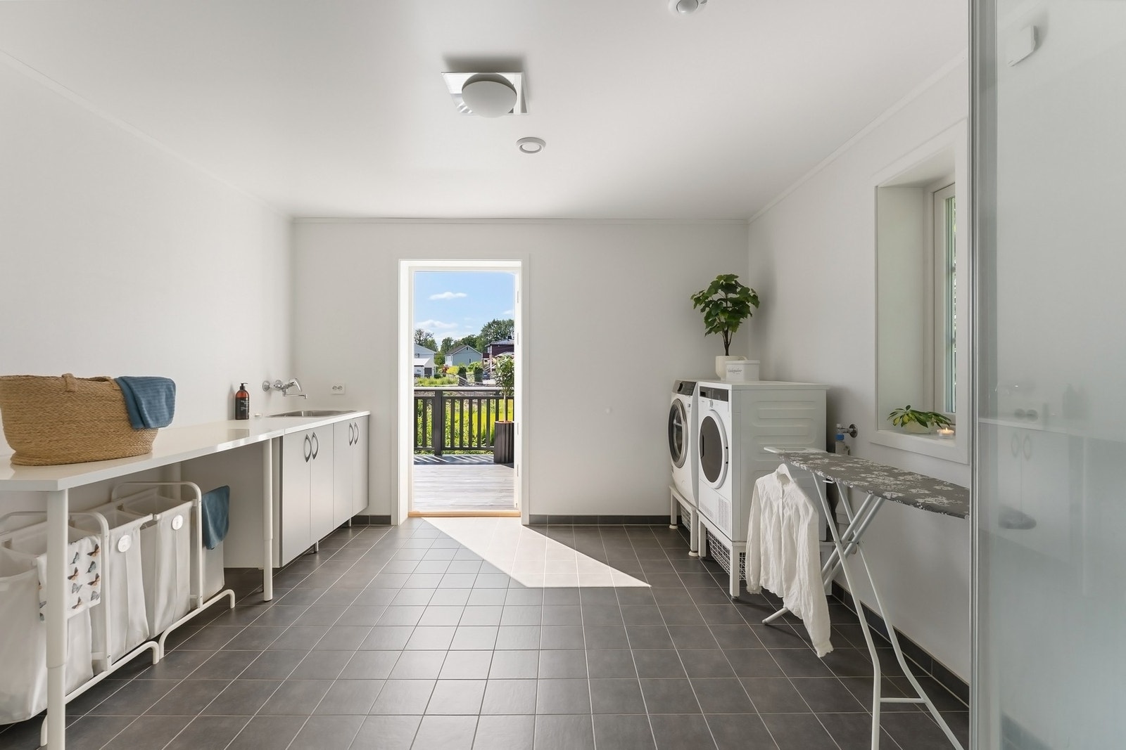 Meget romslig vaskerom med utgang til veranda. På vaskerommet er det dusjkabinett, vegghengt toalett og servant. Galleribilde