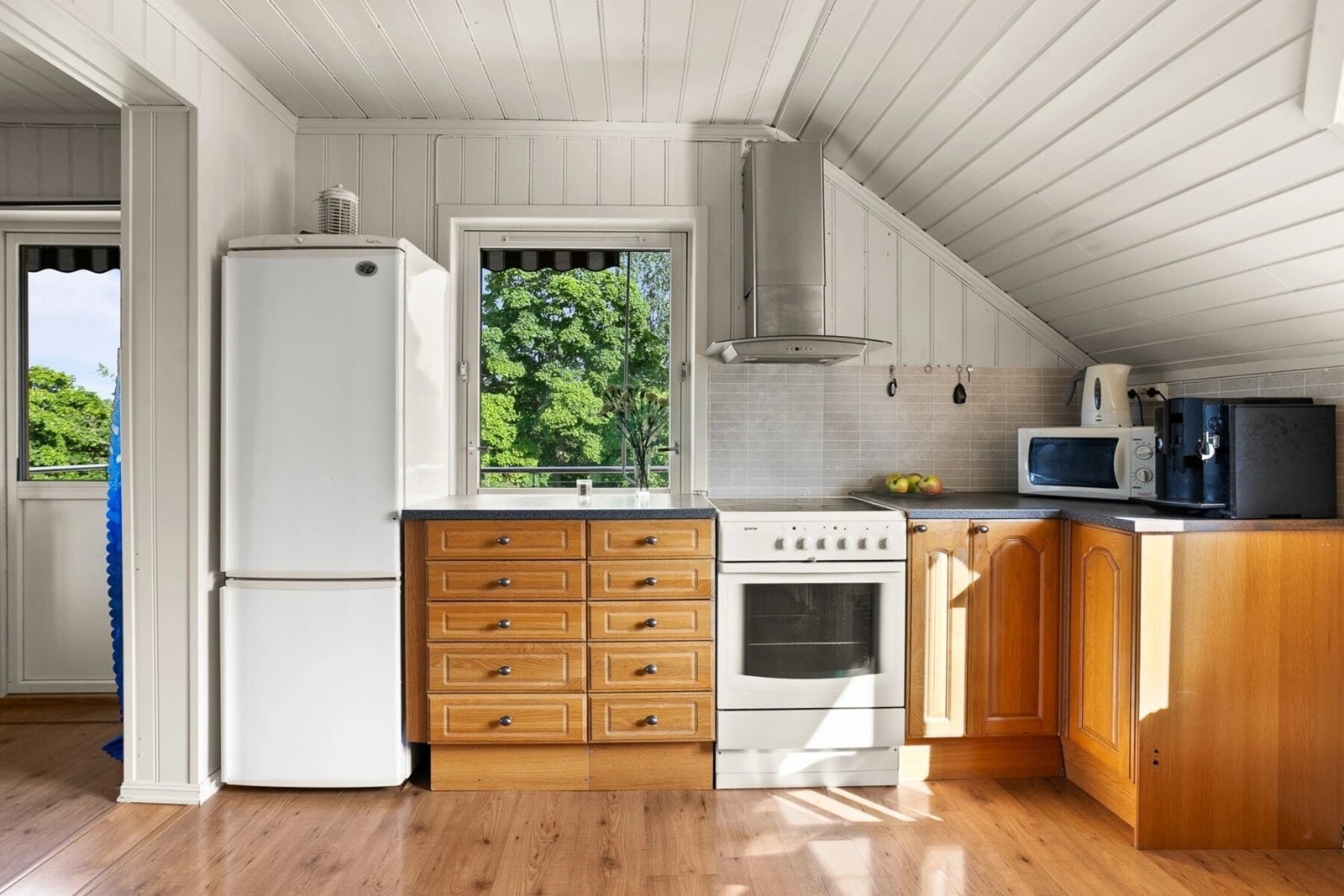 Kjøkkeninnredning med profilerte fronter, benkeplater i laminat, oppvaskkum med ett-greps blandebatteri og ventilator over kokesonen. Galleribilde