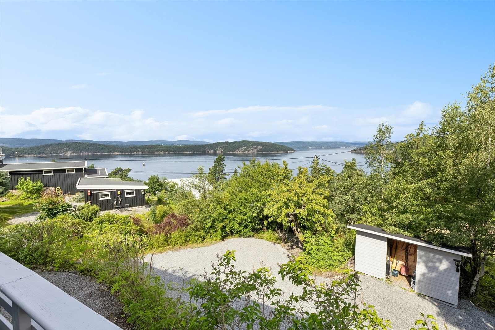 Gruset gårdsplass med rikelig med biloppstillingsplasser og et praktisk vedskjul. Galleribilde