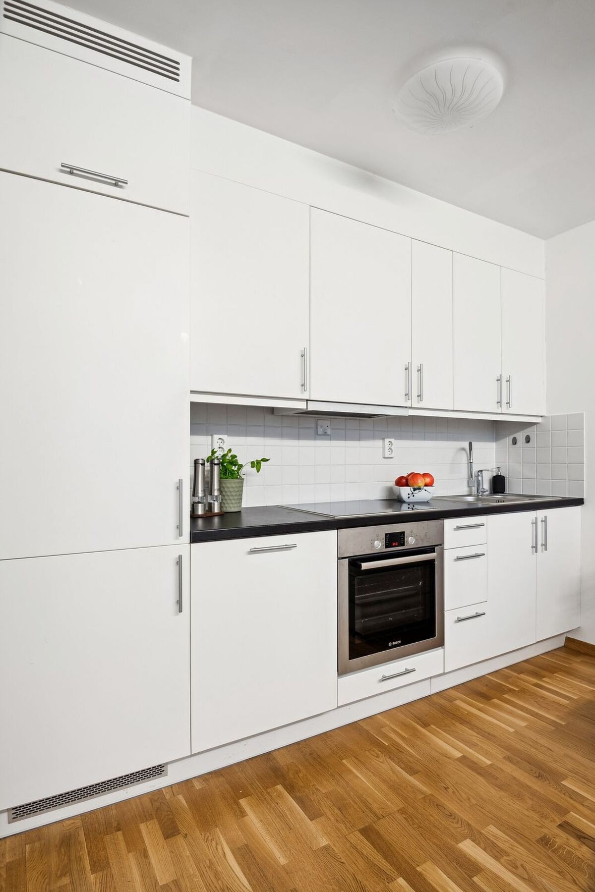 Kjøkkenet er utstyrt med høyskap som gir rikelig oppbevaringsplass, stilrene håndtak og fliser over benkeplaten som gjør rengjøringen enkel. Galleribilde