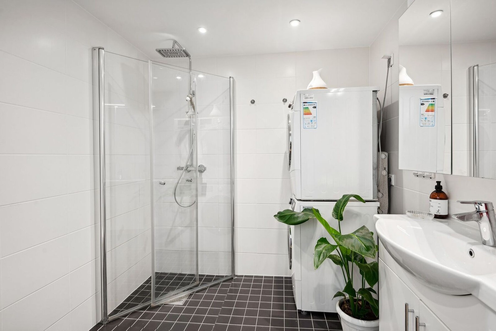 Moderne bad med dusjhjørne, vaskemaskin og tørketrommel. God plass og stilrent, med praktiske løsninger. Galleribilde