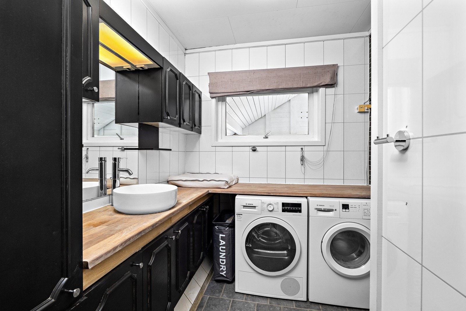 Eldre bad med opplegg for vaskemaskin og plass under benk til både vaskemaskin og tørketrommel. Galleribilde