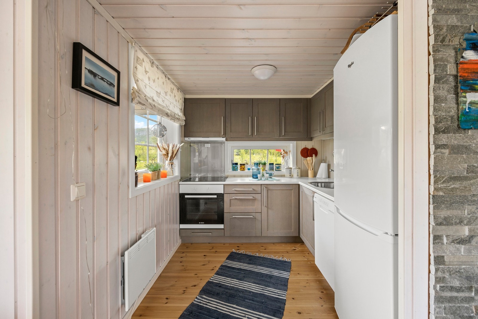 Kjøkken med integrert platetopp og stekeovn, samt avsatt plass for kjøleskap og oppvaskmaskin Galleribilde