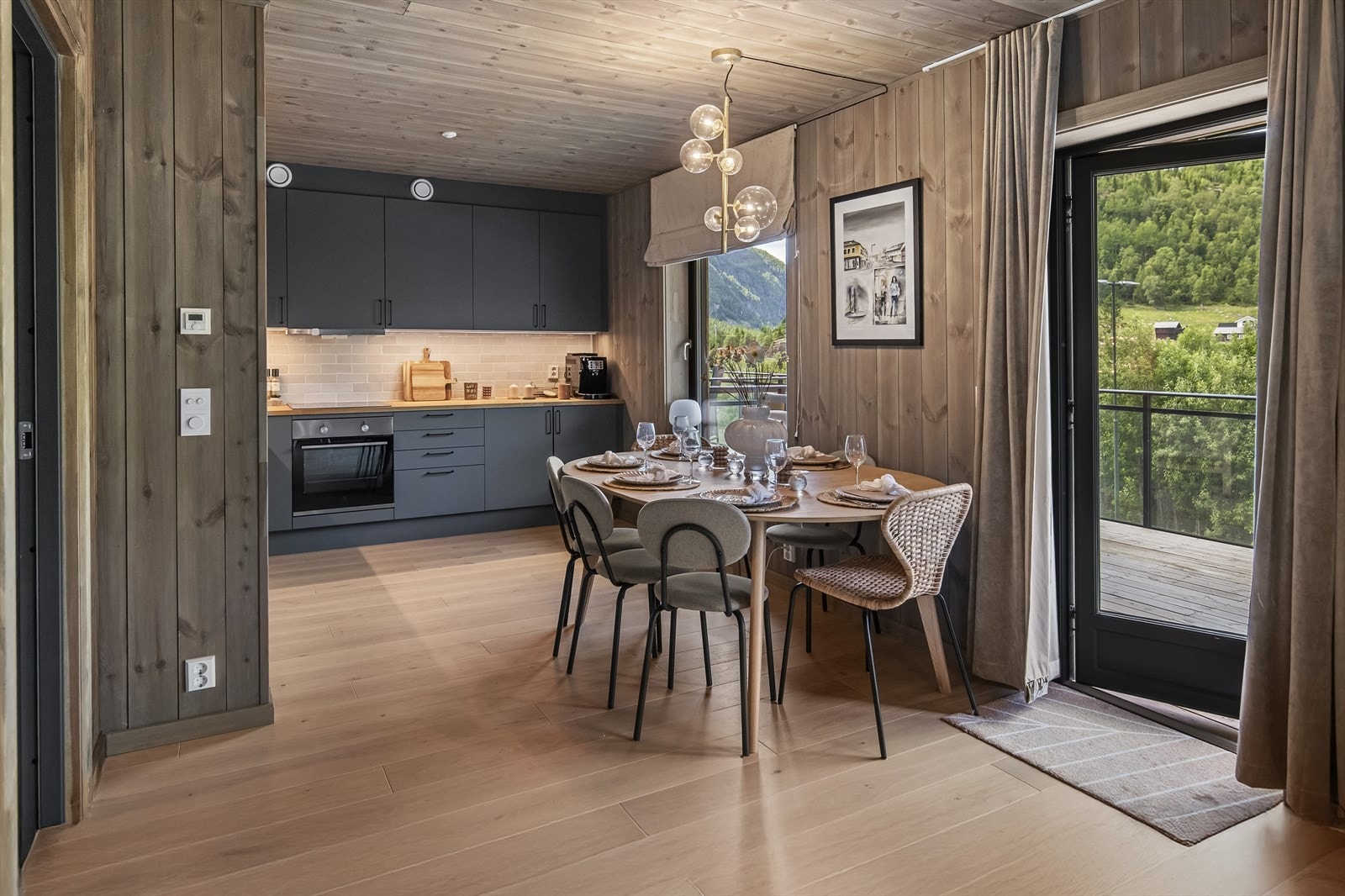 Innredningen har takoppforede skap, grå, slette fronter og benkeplate i heltre. En sort oppvaskkum er nedfelt i benken og over er det delikate, grå fliser og avtrekk fra ventilator. Galleribilde