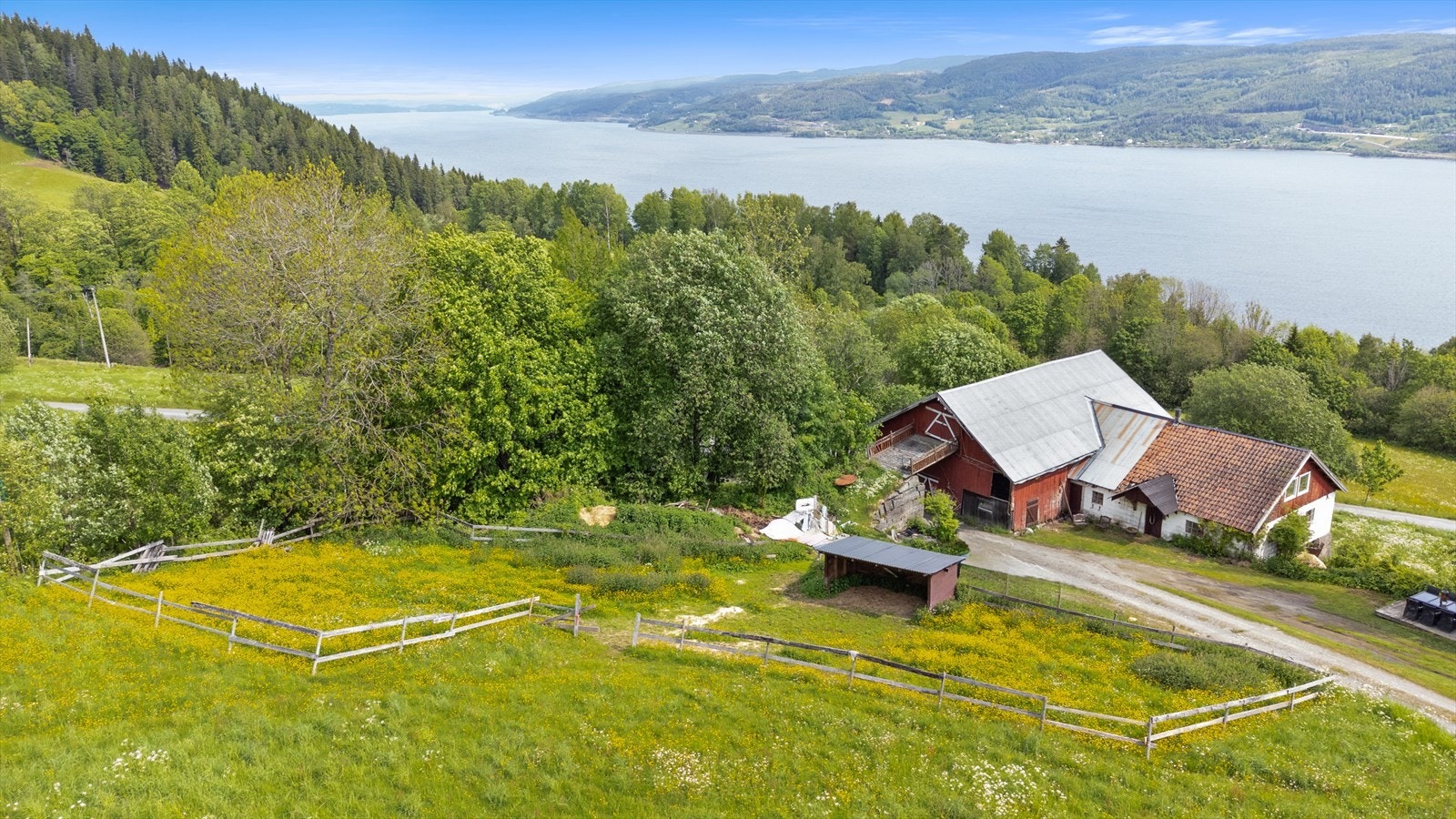 Eiendommen har et innbydende tun med låve, stabbur og anneks, omgitt av grønt landskap. Galleribilde