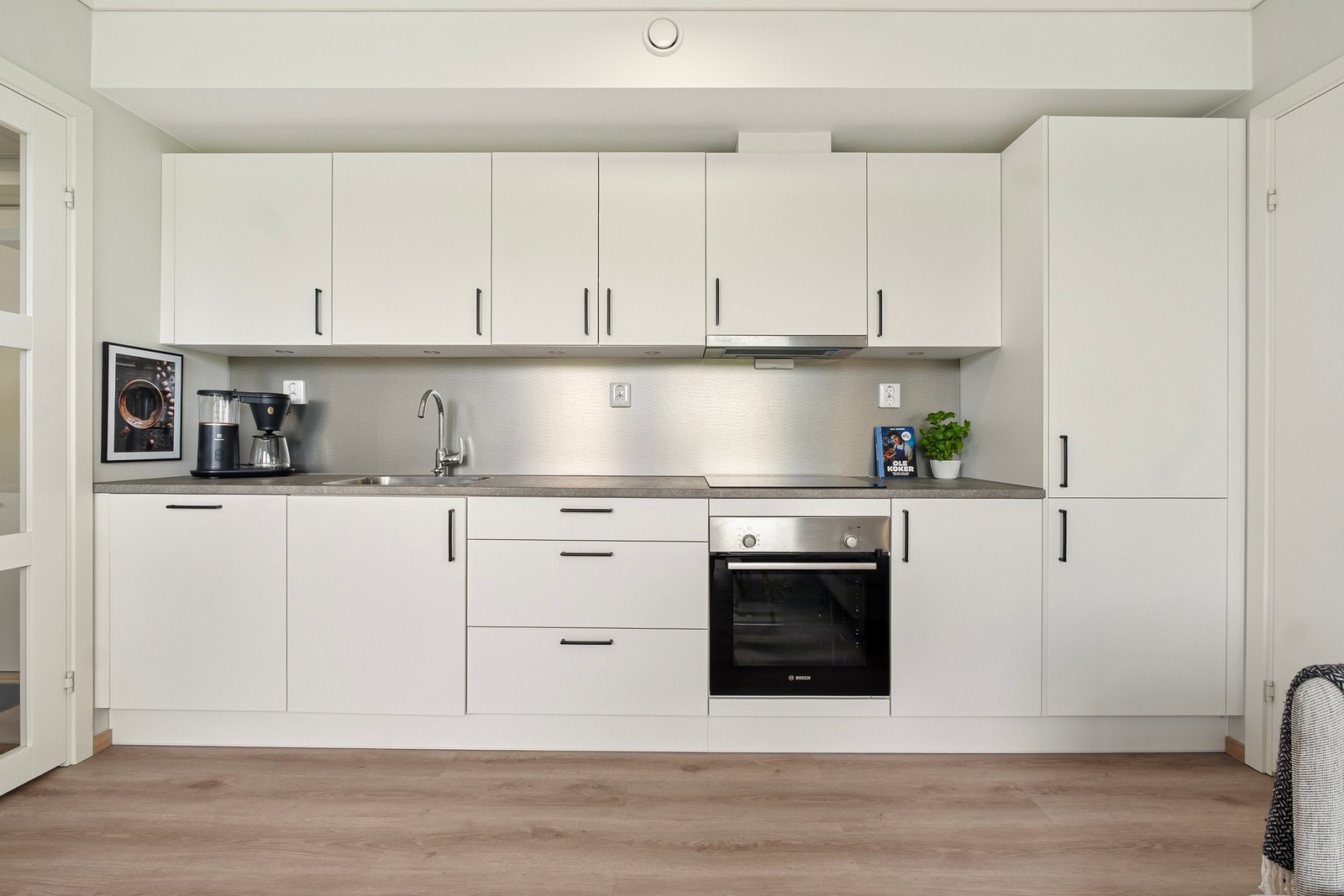 Kjøkkenet er moderne med slette fronter, integrerte hvitevarer, fliser over benk og waterguard under vask. Galleribilde