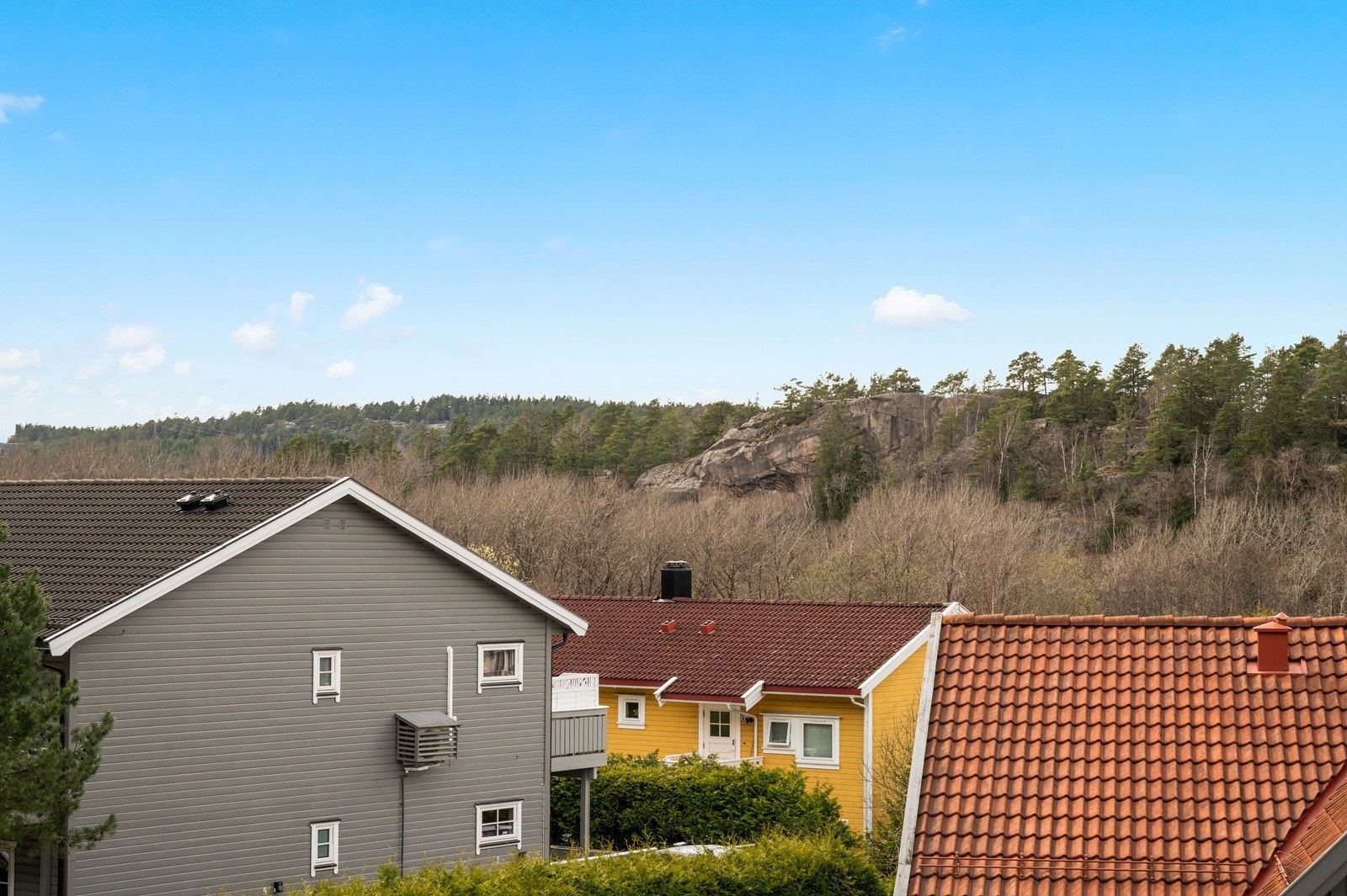 Utsikt fra veranda hvor man ser over takene på eiendommen som ligger lavere i terrenget. Galleribilde