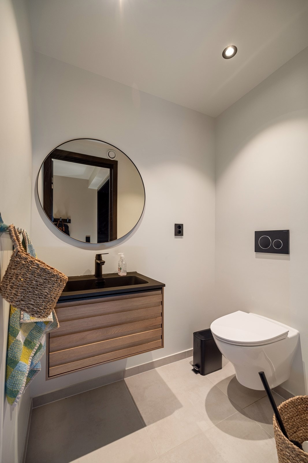 Toalettrommet har lekre fliser på gulvet og malt platekledning på veggene. Rommet inneholder veggfestet toalett, flott servantinnredning og speil over servant. Galleribilde