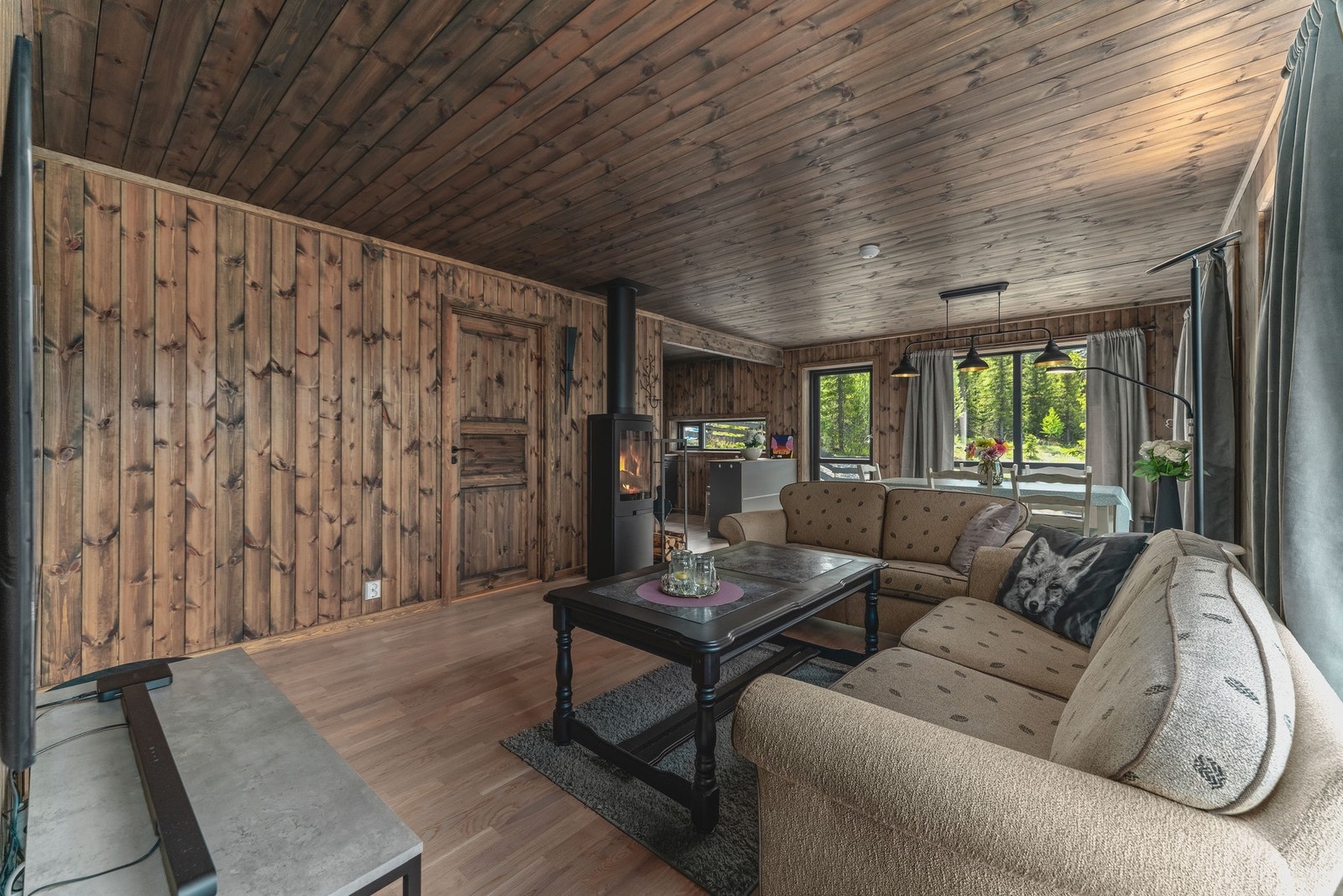 Vegger og tak er kledd i mørkt trepanel som skaper en varm og koselig stemning. Galleribilde