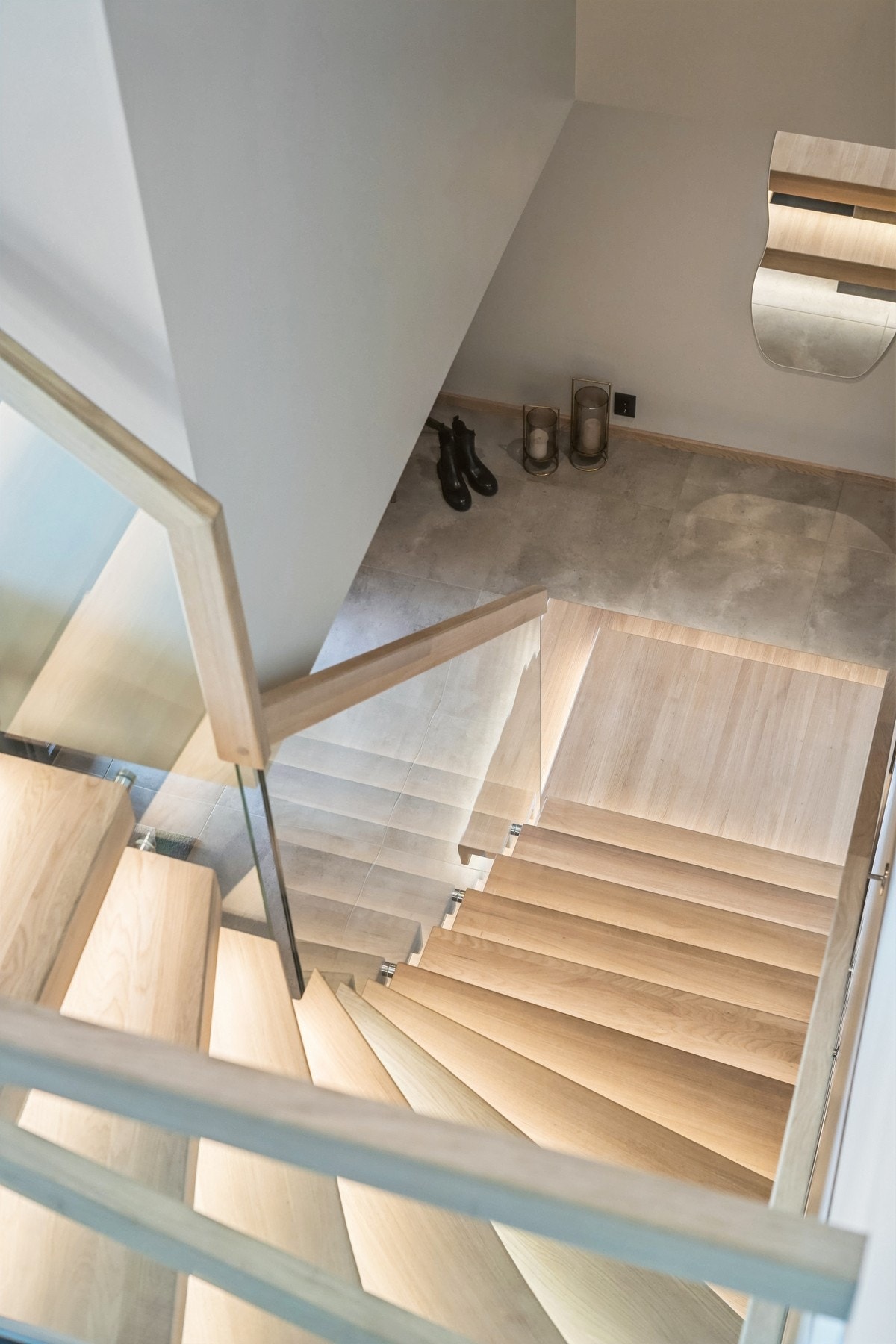 En vakker eiketrapp med diskret belysning og elegant glassrekkverk setter en eksklusiv tone i boligen. Galleribilde