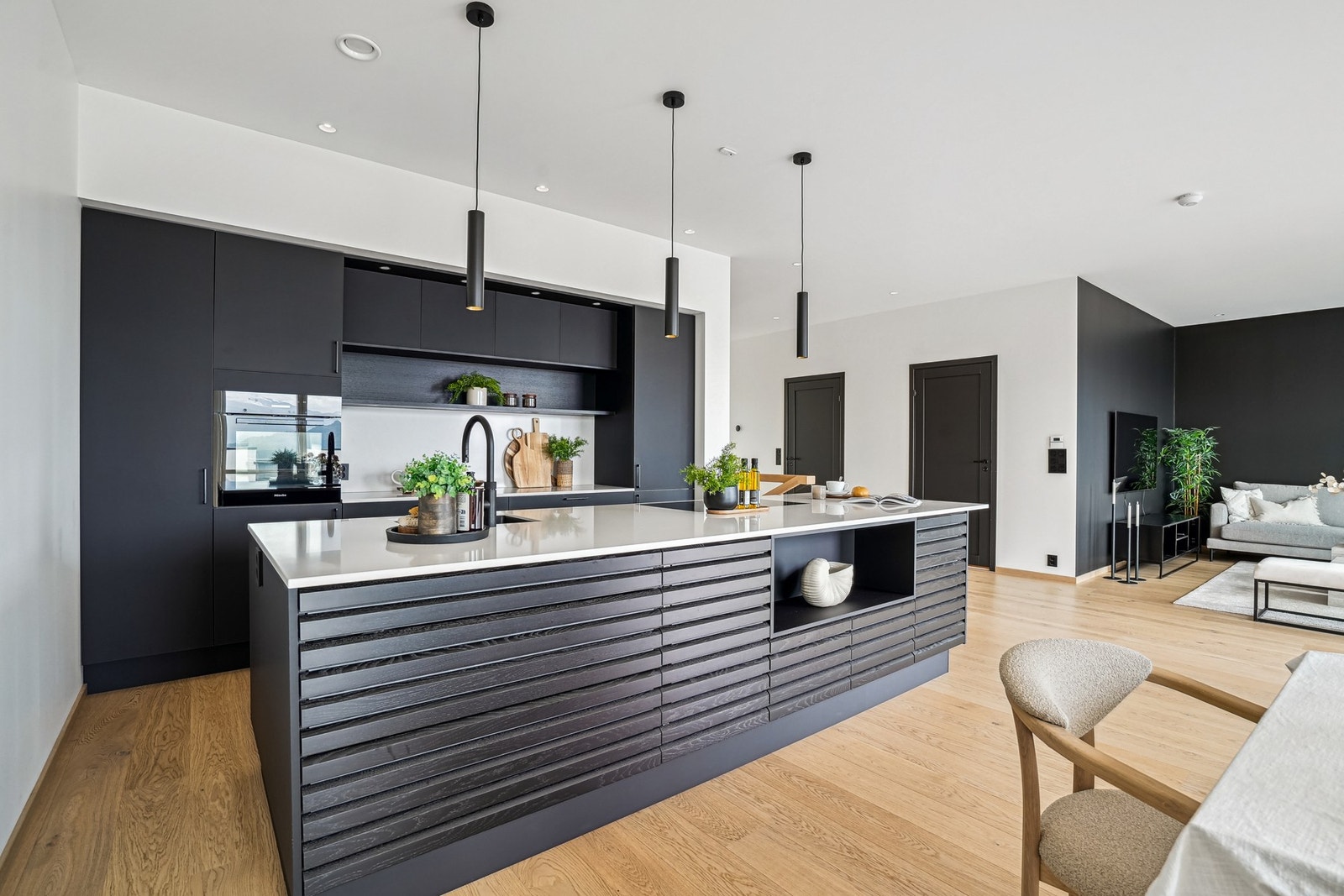 - med mørke fronter, spiler på kjøkkenøy og benkeplate av komposittstein. Galleribilde