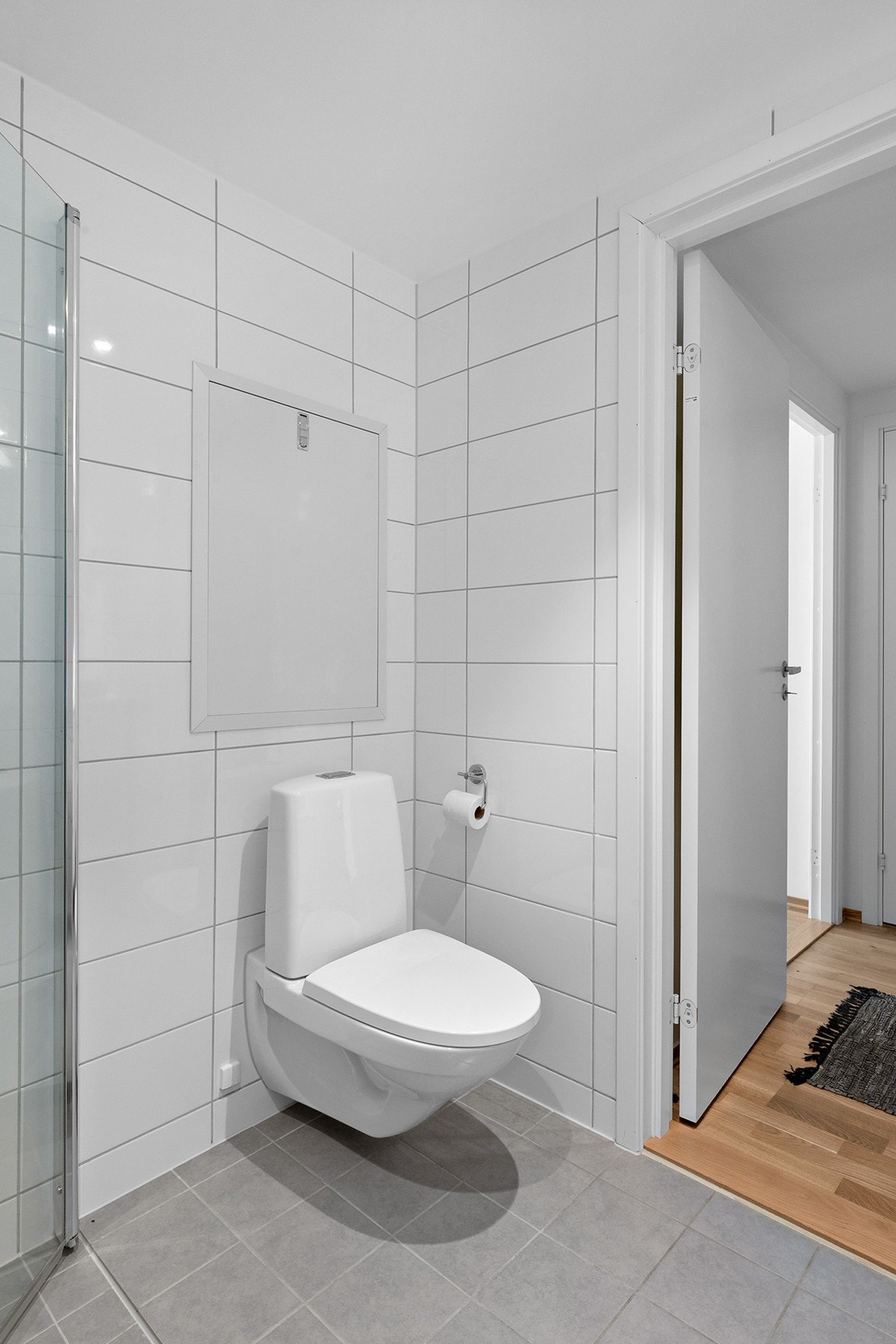 Badet består av vegghengt wc, enkel servant med skuffer og skap under, stor speil og inn -og utadslående dusjdører. Galleribilde