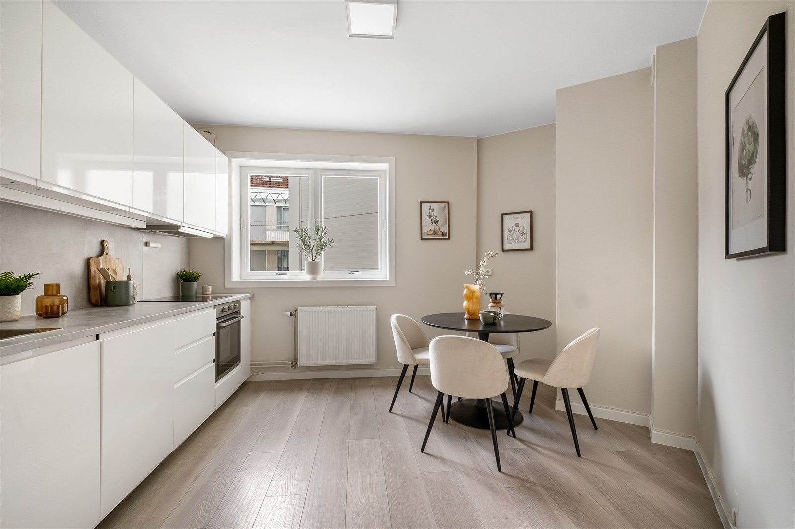 Pen kjøkkeninnredning fra IKEA med glatte fronter og integrerte hvitevarer. Rommet har plass til et spisebord. Galleribilde