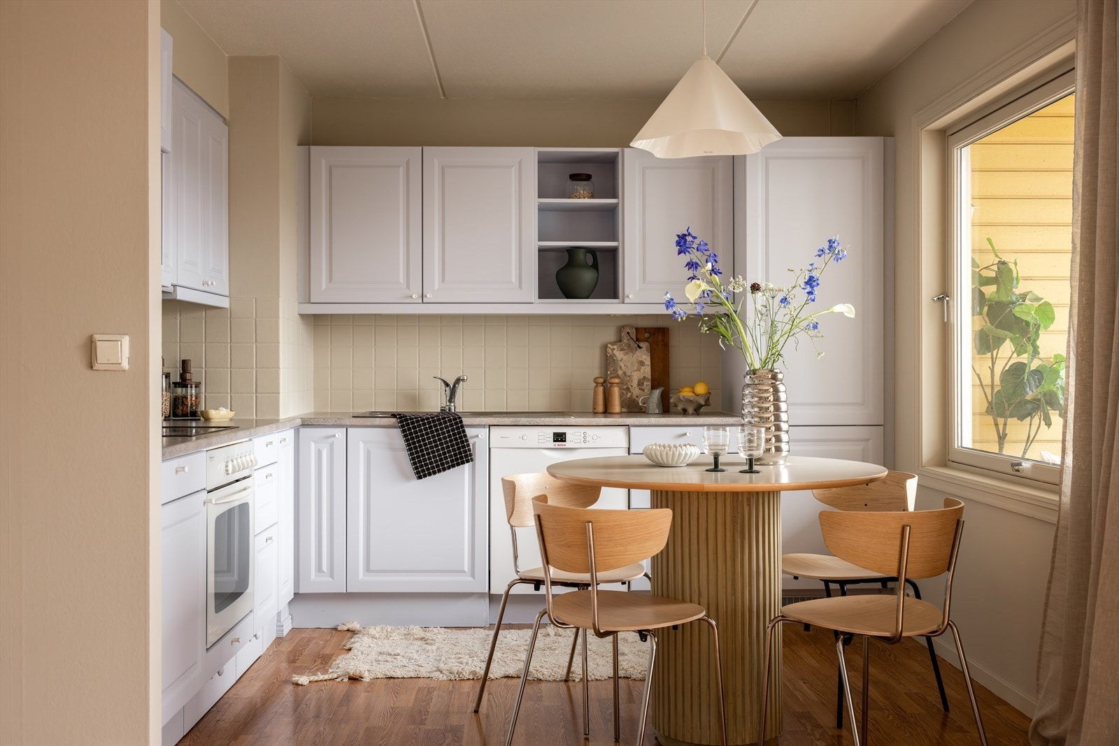 Praktisk kjøkkeninnredning med benkeplate av laminat, fliser mellom over og underskap og masse oppbevaringsmuligheter. Galleribilde