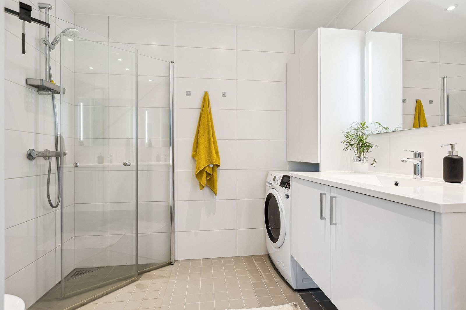 Lekkert flislagt bad med varme i gulv, innfellbare dusjvegger, wc og vaskemaskin Galleribilde