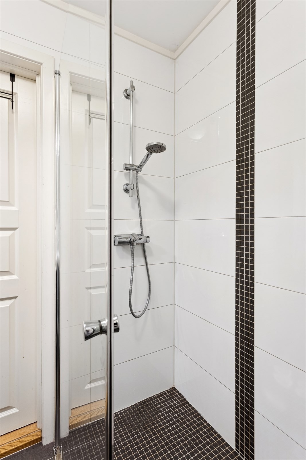 Badet består av en vegghengt klosett, dusj med vegger, og servant med skuffer under. Galleribilde