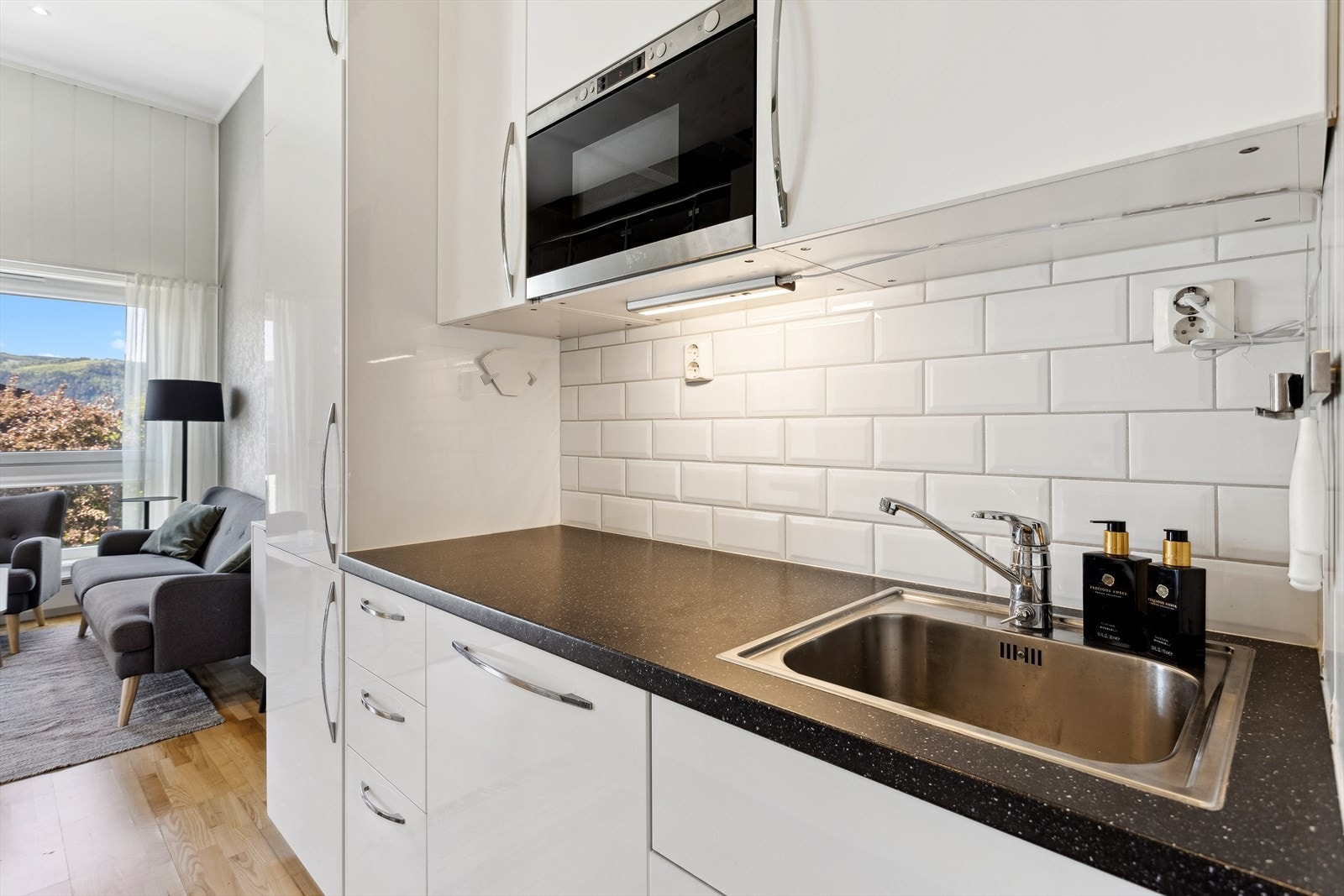 Det er fliser på veggen mellom over- og underskap, samt belysning under overskapene. Galleribilde