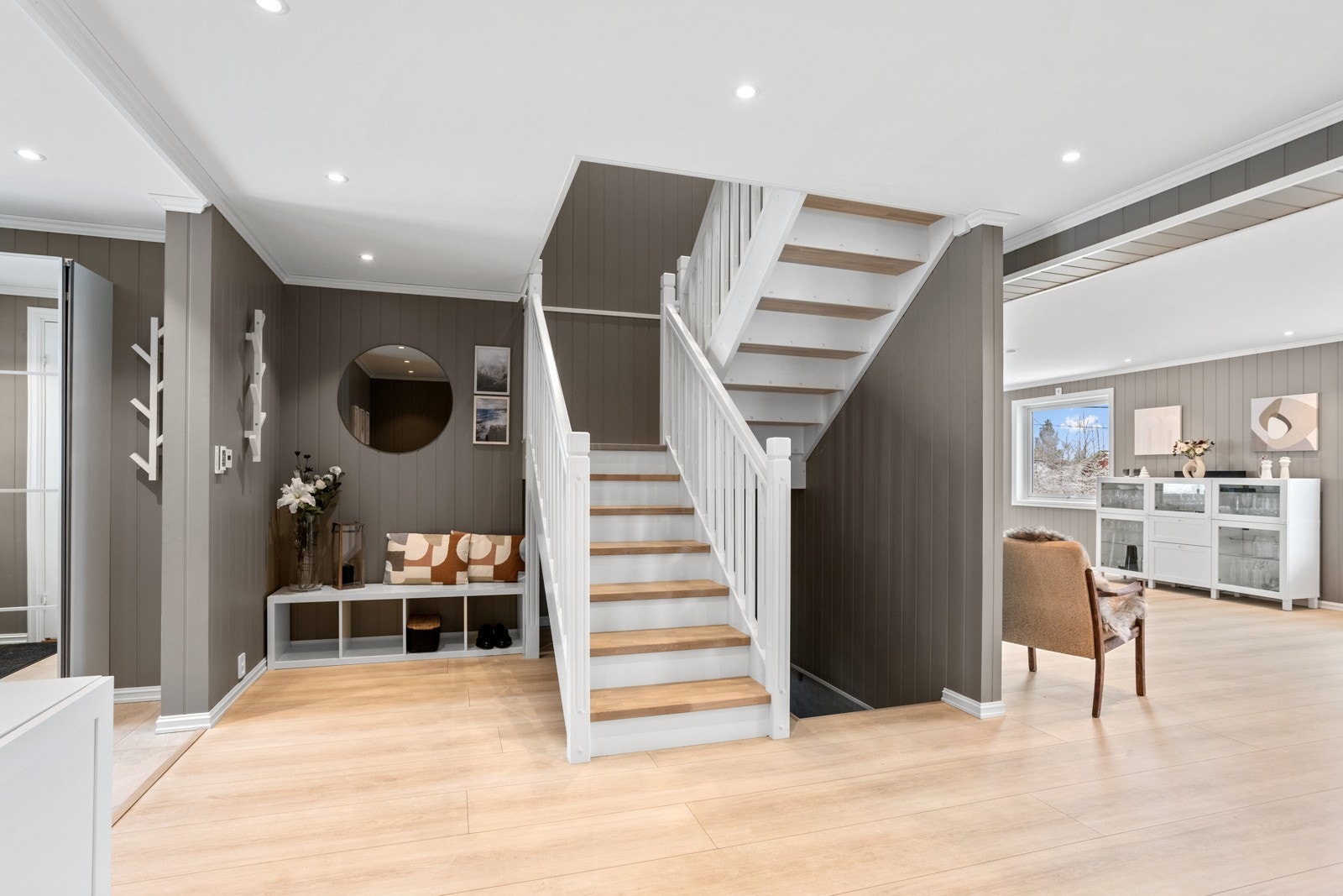 Hallen har downlightsbelysning og lyst parkettgulv som strekker seg videre inn til resterende rom i huset. Galleribilde