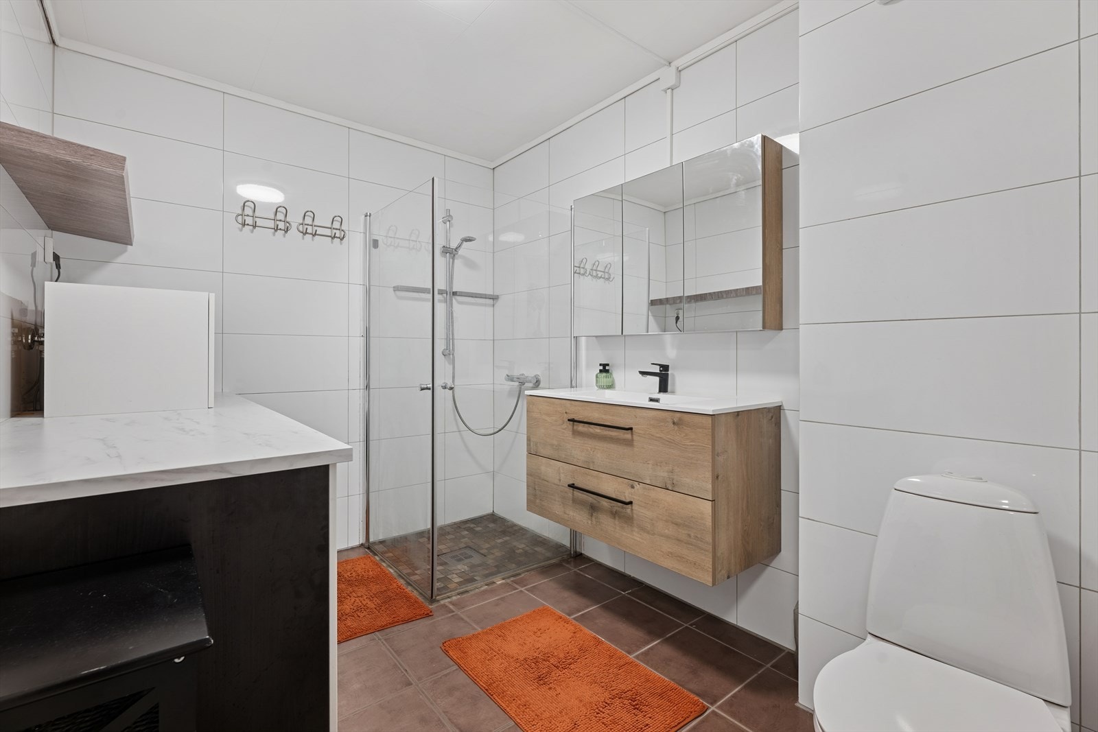 Det er montert en nyere og pen baderomsinnredning med skuffeseksjon og nedfelt servant, toalett og belyst speilskap. Det er en stor og herlig dusjsone med innfellbare glassdører. Galleribilde