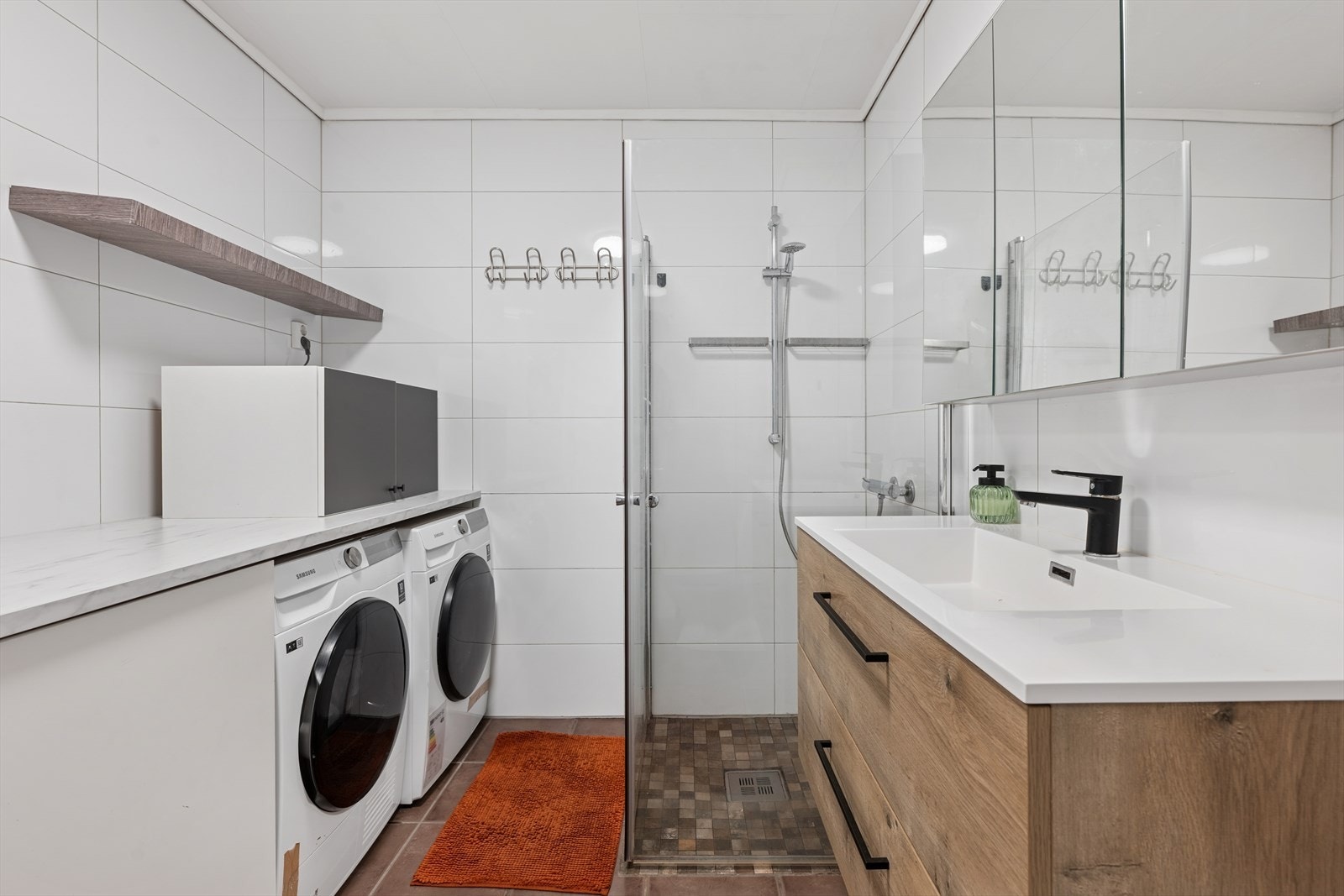 Leiligheten har et delikat og stort bad med flislagt gulv og vegger. Det er etablert en egen "vaskeromsnisje" med opplegg for vaskemaskin, skaplass og benk for godt arbeidsareal. Galleribilde