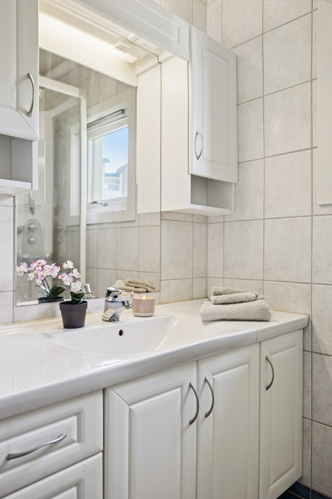 Badet har servant med underskap, speil, veggskap, toalett og dusjhjørne. Galleribilde