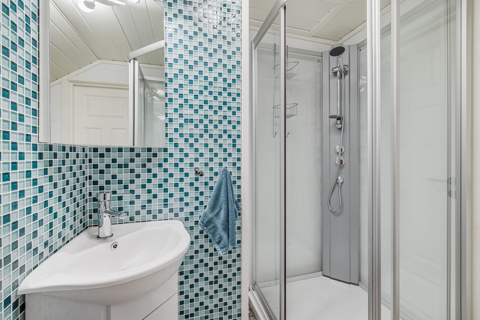 Baderommet er utstyrt med servantskap, speil med belysning, dusjkabinett og gulvstående toalett. Galleribilde