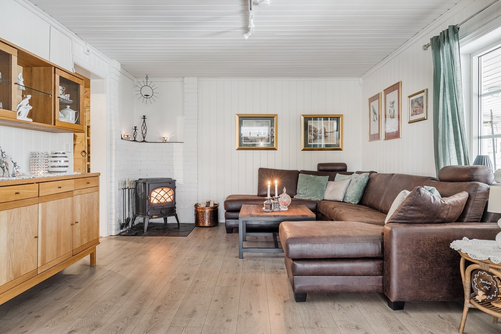 Videre kommer du inn til en lys og romslig stue. I hjørnet av stuen har du koselig vedovn som både gir god varme og bidrar til ekstra hygge. Galleribilde