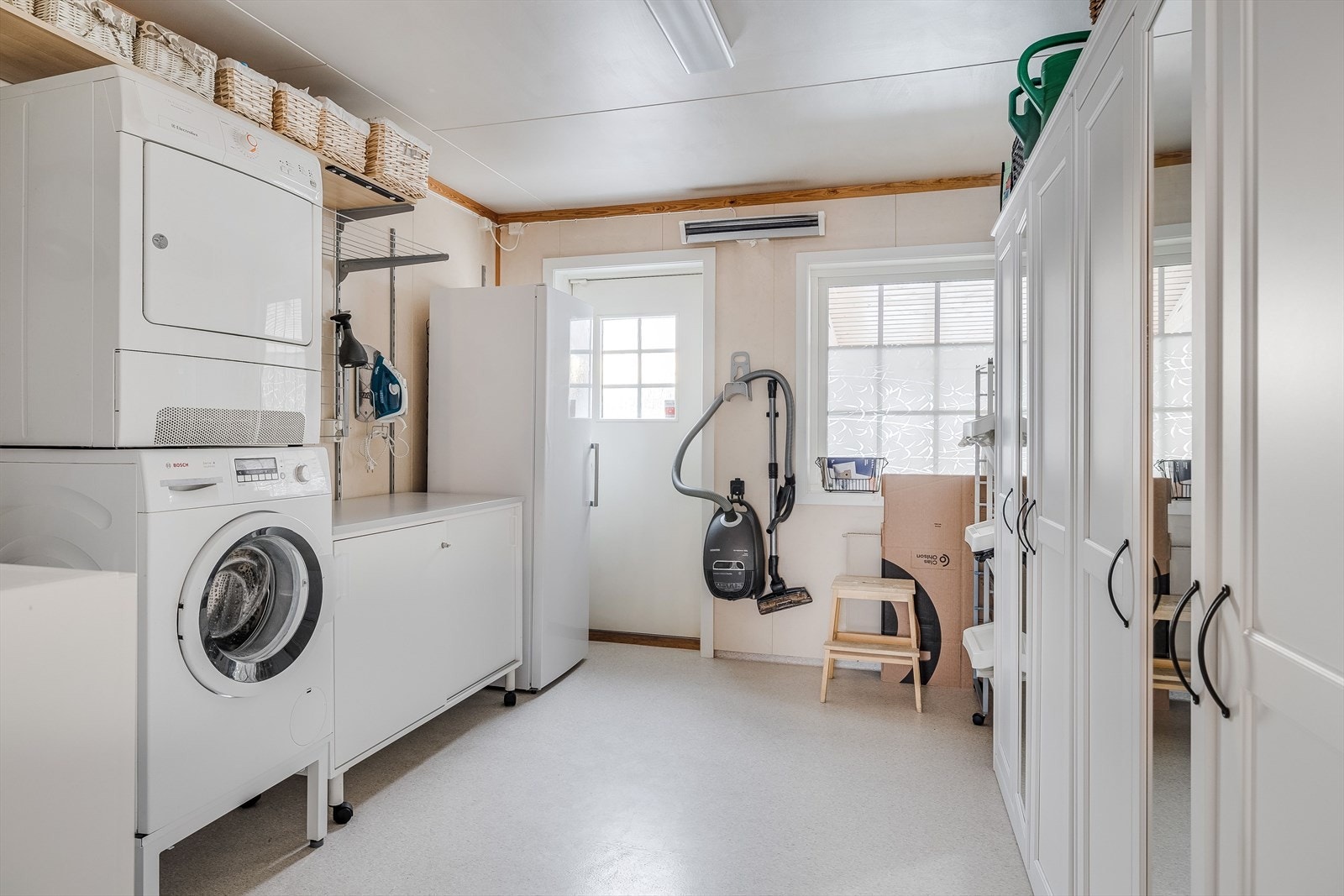 Fra badet har du videre adkomst til et praktisk vaskerom med egen utgang. Vaskerommet har belegg på gulv og er utstyrt med vaskekum, opplegg for vaskemaskin og flere garderobeskap. Galleribilde