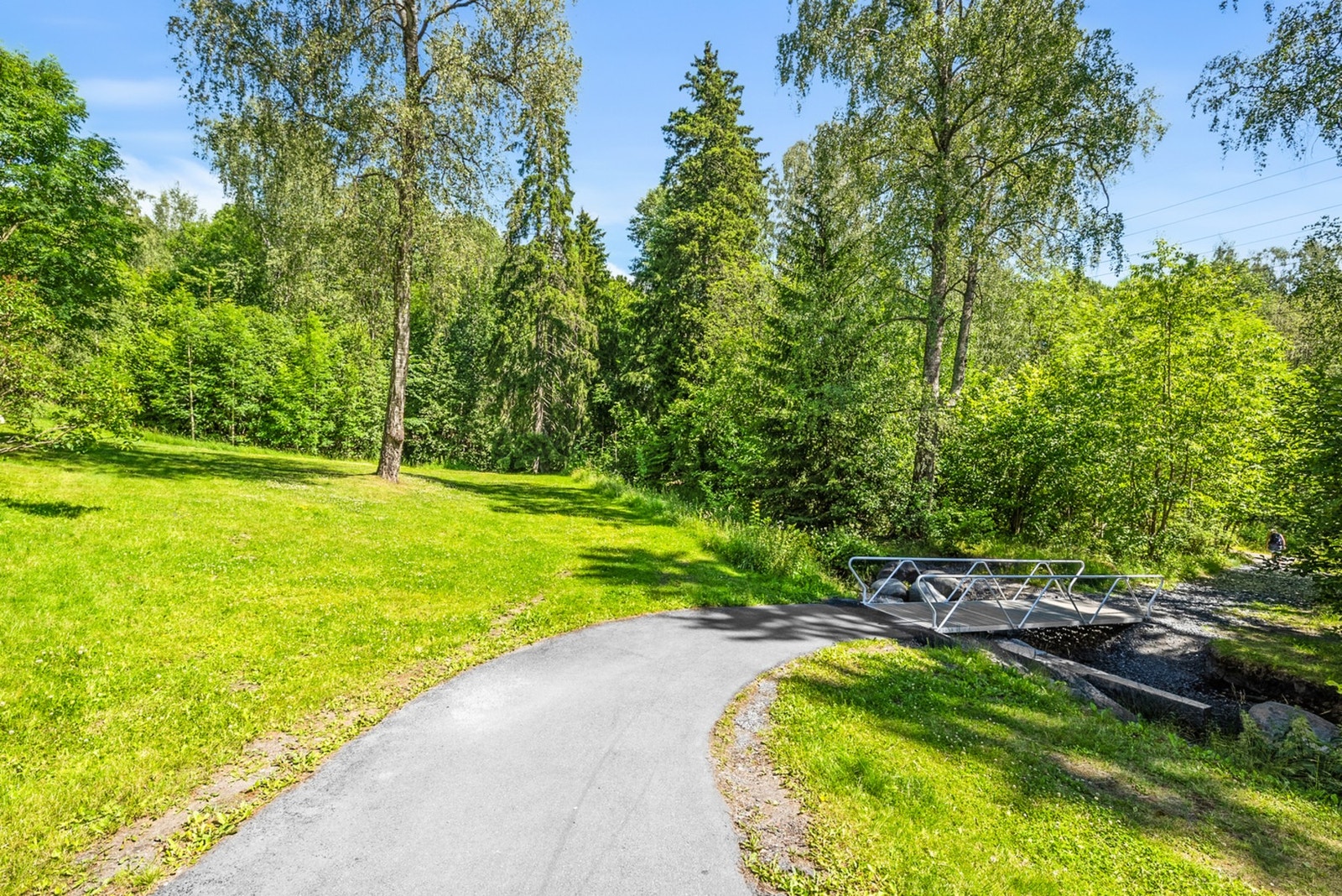 Stort fellesareal opparbeidet med asfalterte adkomstveier/ plasser, gressplen, beplantning, trær, lekeapparater, parkeringsarealer m.m. Galleribilde