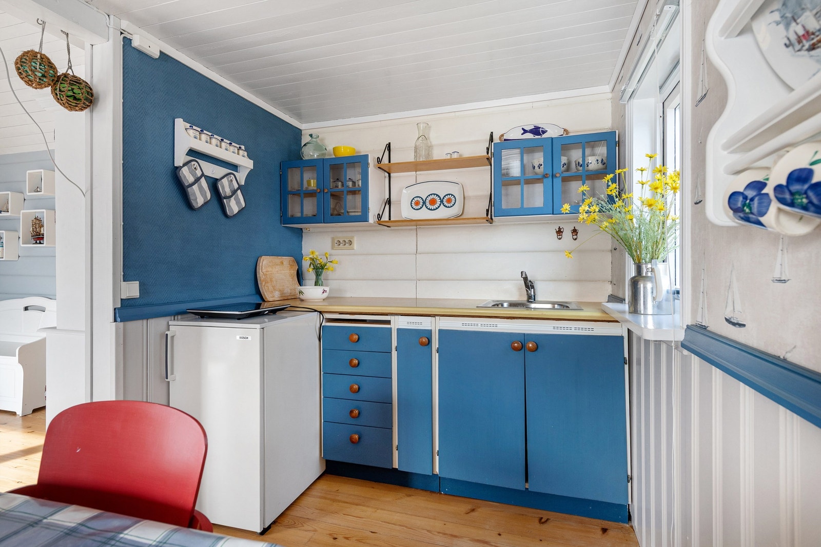 Enkel kjøkkeninnredning med glatte fronter og laminat benkeplate. Frittstående koketopp og kjøleskap. Galleribilde