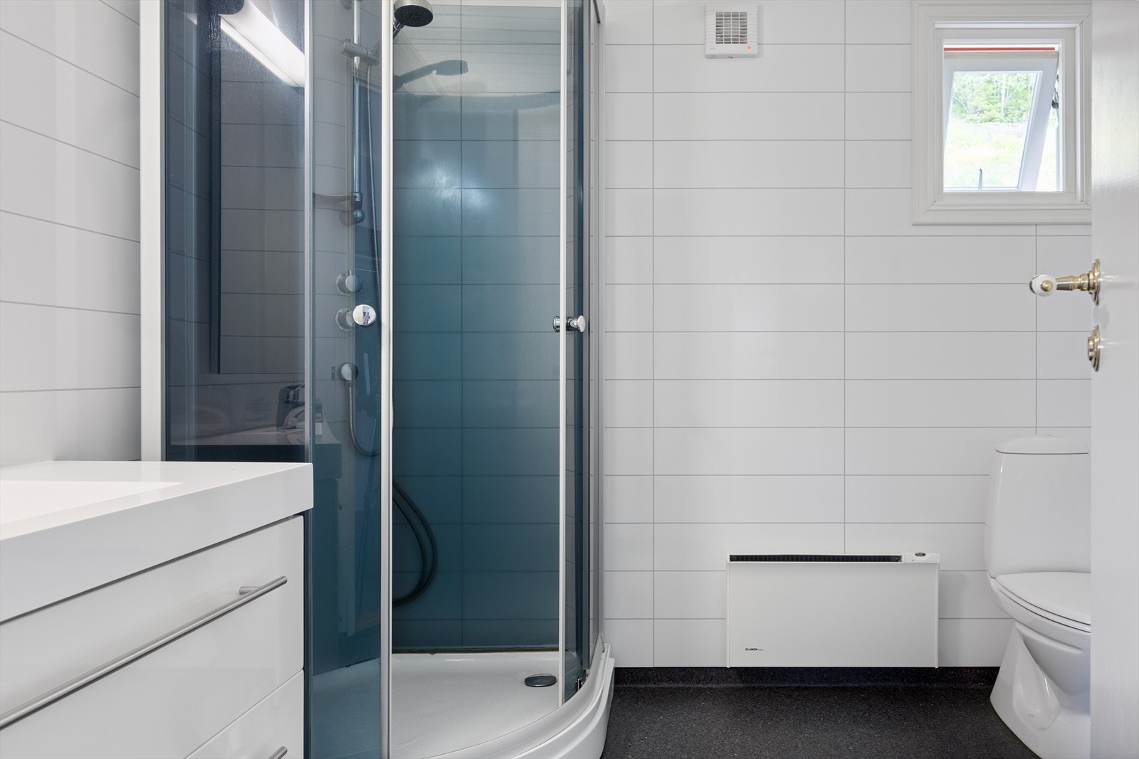 Badet har baderomsplater og gulvbelegg. Innredning med servant, toalett og dusjkabinett. Galleribilde